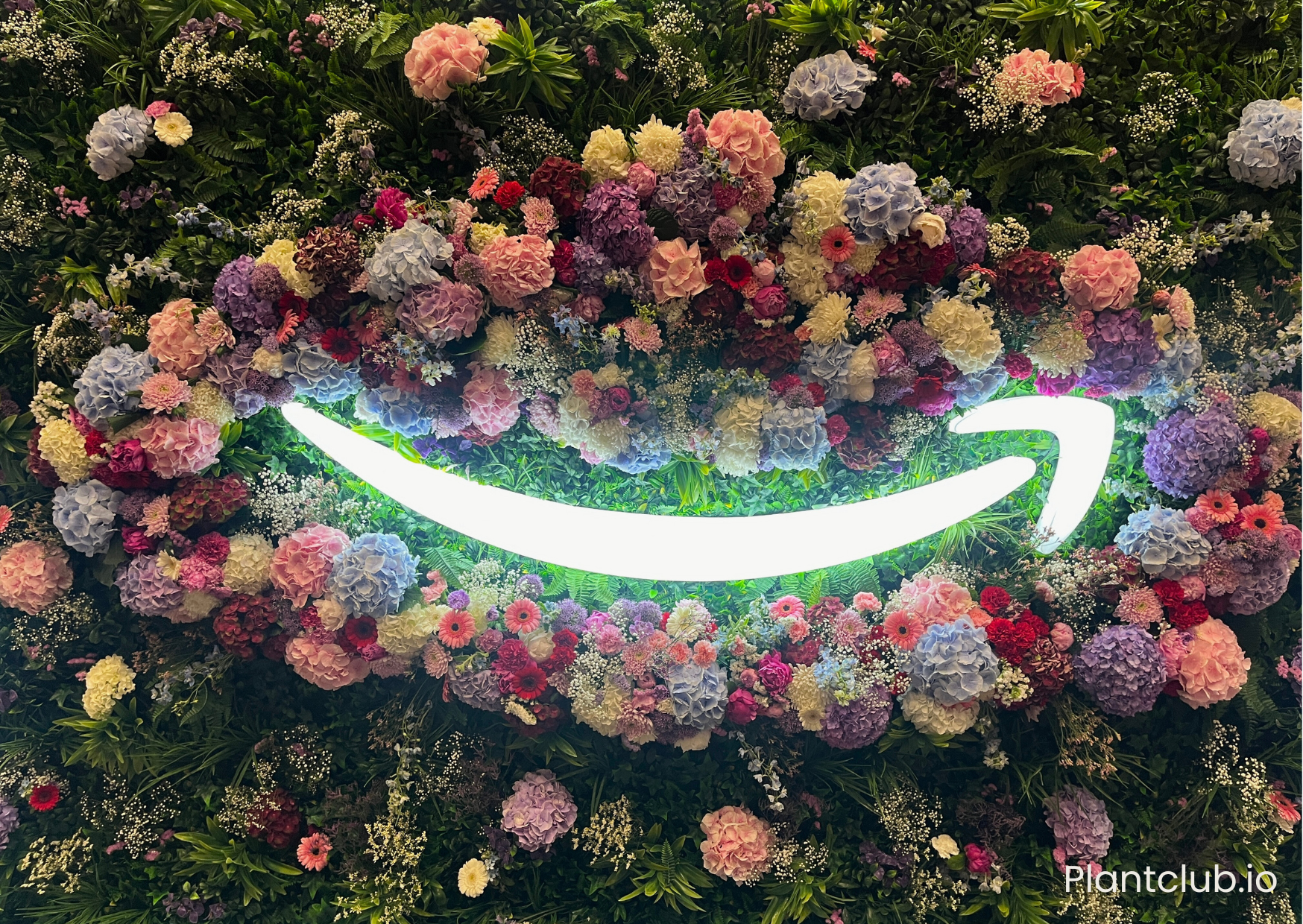 A green wall using plants and flowers around a neon logo