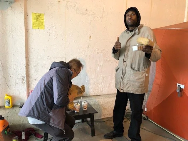 Eric preparing food while a homeless man enjoying the hot soup