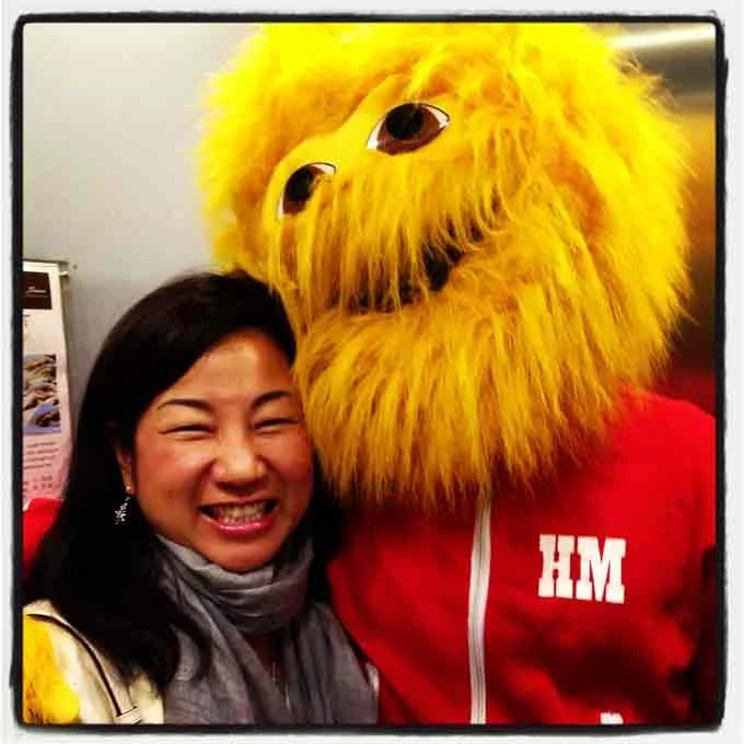 alice smiling next to Honey Monster (big yellow fuzzy monster) in a red track suit