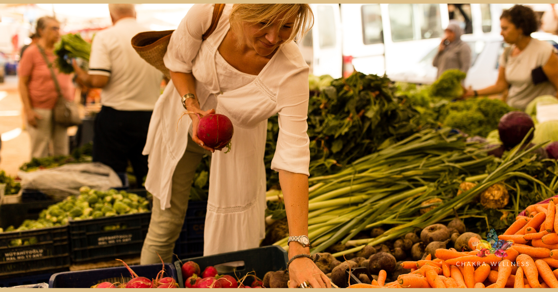 A woman shopping at a farmer's market, choosing vegetables including carrots, potatoes, radishes, and leafy greens.