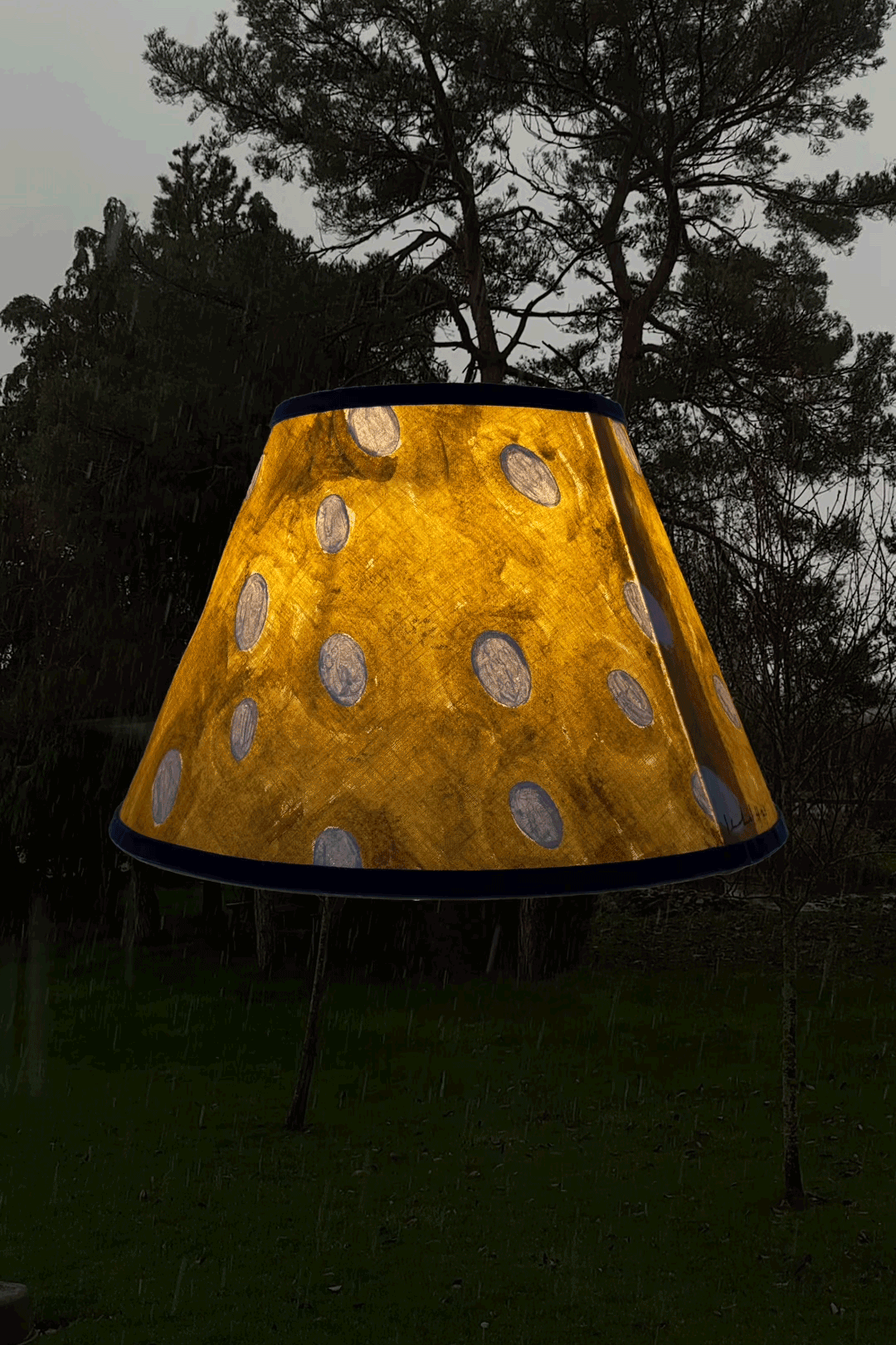 Flurry linen lampshade by artist, Isobel Hill. Lamp is rotating whilst glowing, snow falls in the background.