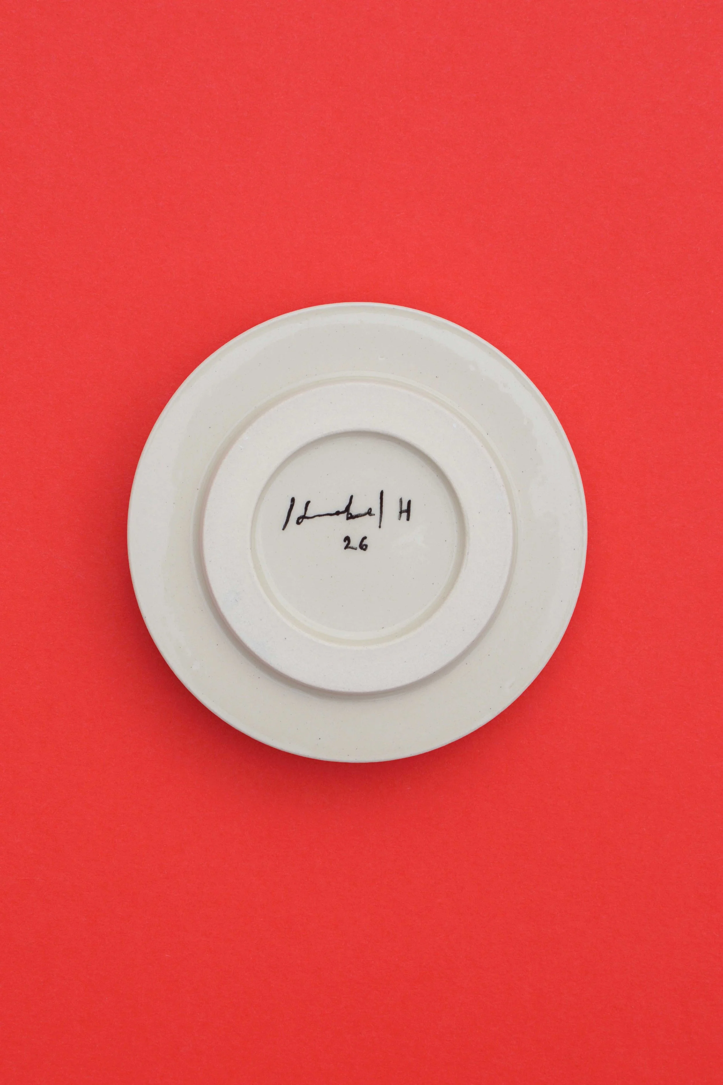 Back of stoneware ceramic coaster set by artist, Isobel Hill. Artist signature and date is hand painted in black underglaze.