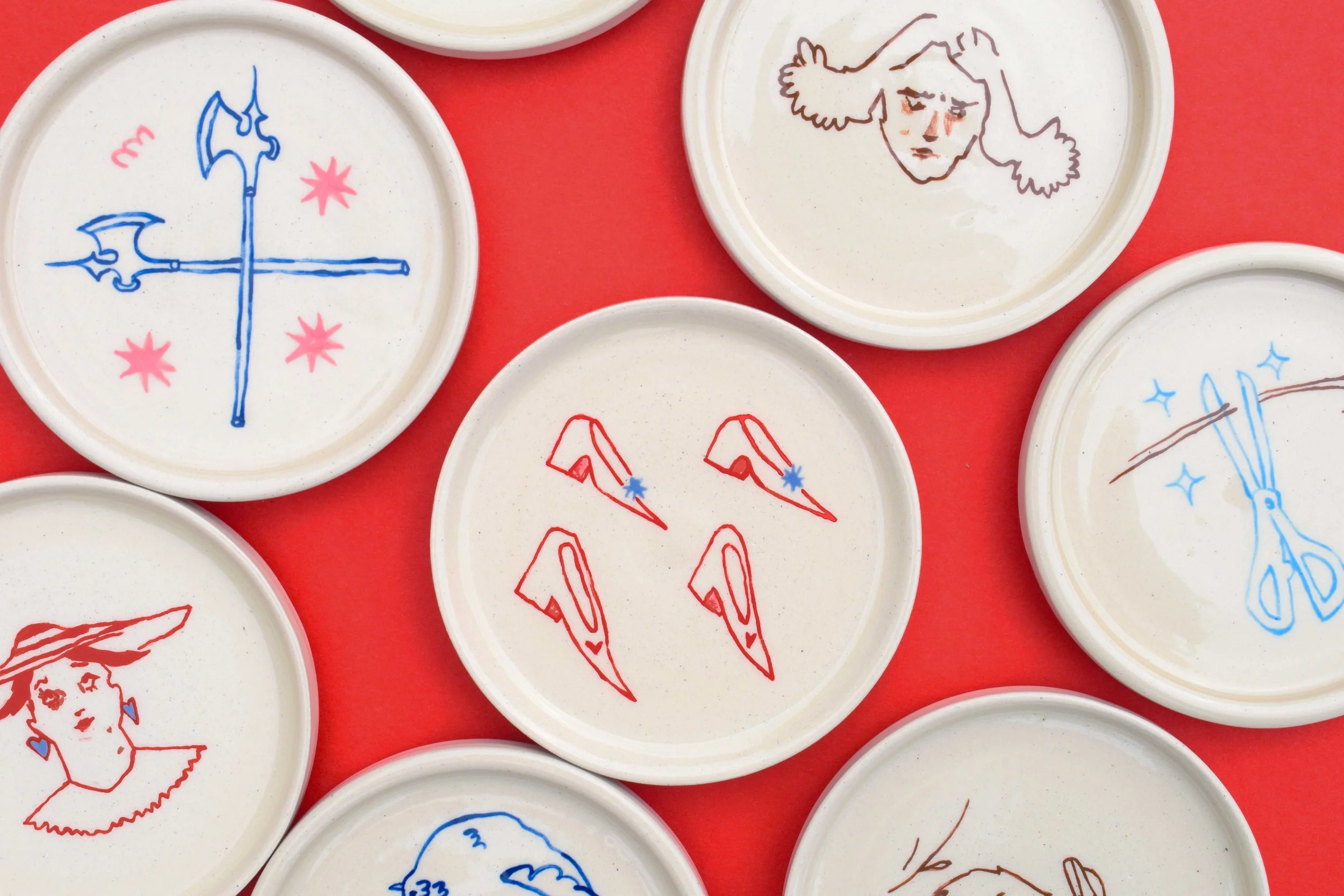 Stoneware illustrated ceramic coasters by artist, Isobel Hill. Coaster feature artworks of axes, people, heeled shoes and scissors in pink blue, brown and red.