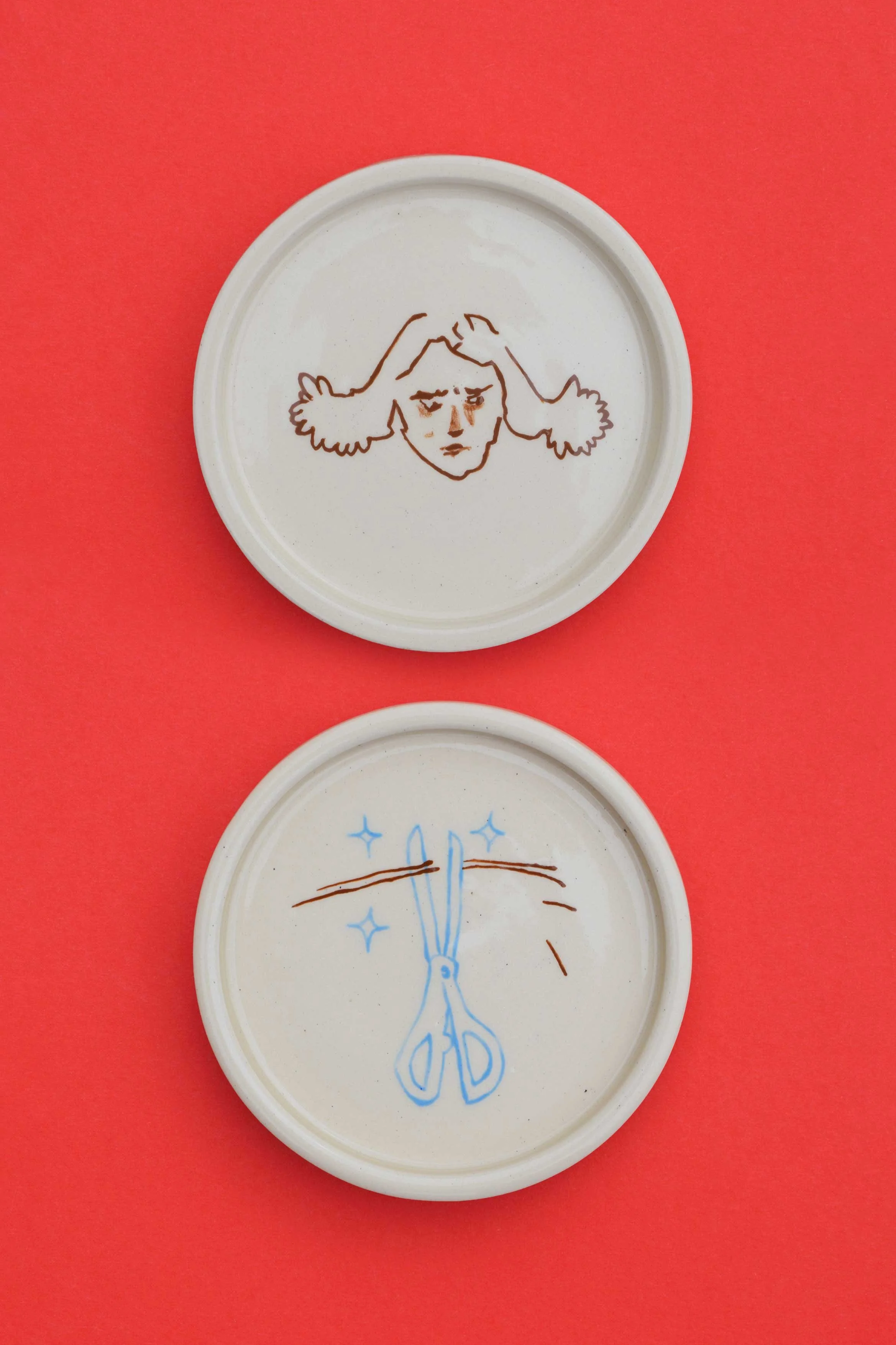 Stoneware ceramic coaster set by artist, Isobel Hill, featuring a person with brown hair looking irritated and a pair of blue scissors.
