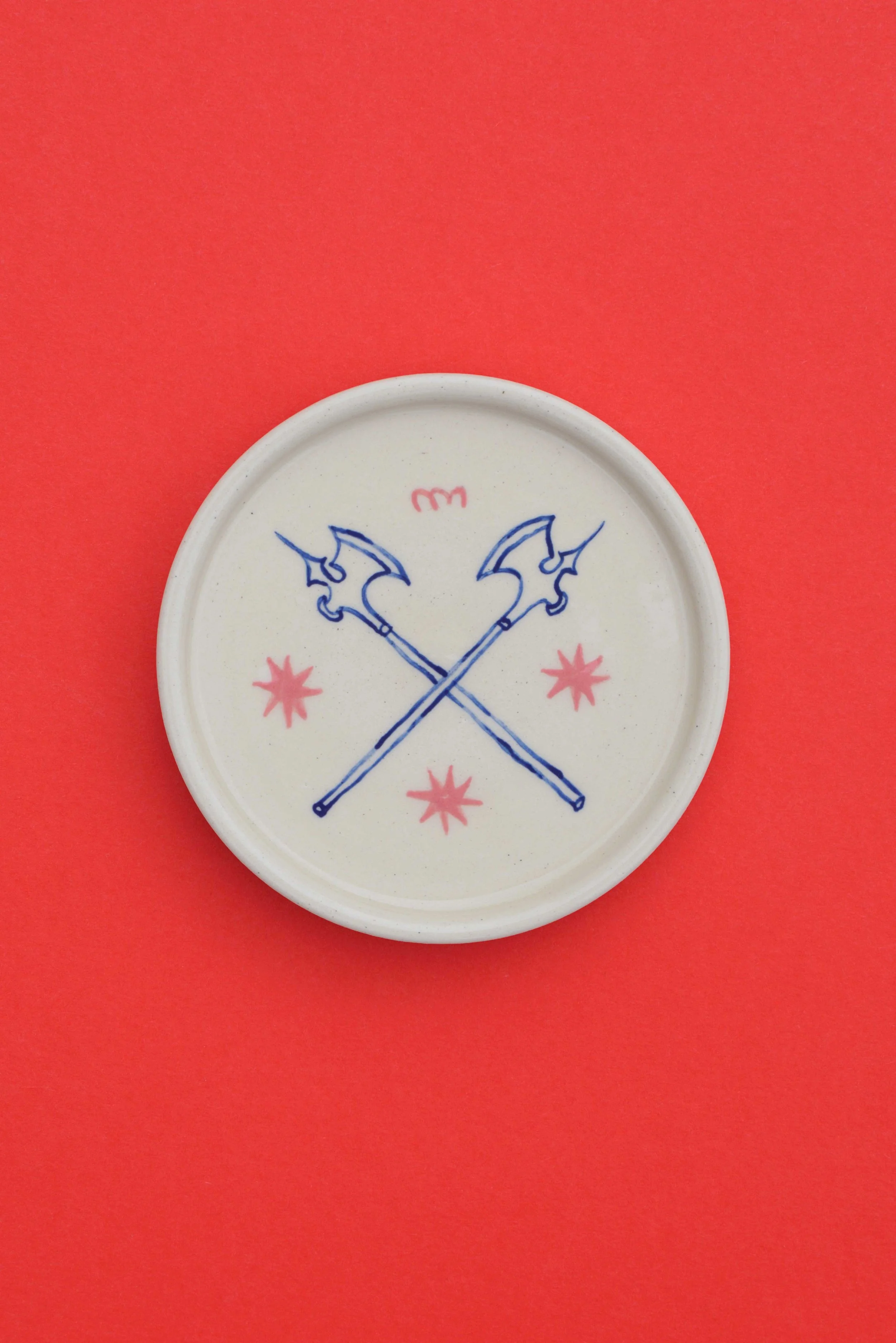 Stoneware ceramic coaster set by artist, Isobel Hill, featuring a pair blue crossed axes, pink stars and a pink squiggle.