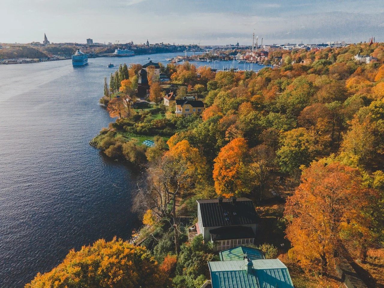 A sea of autumn color spreads across Djurg&aring;rden, where marinas, forest paths, and treetops blend into one Nordic tapestry. Stockholm in fall is especially striking from above, with water and woodland sharing the frame. This island becomes most 