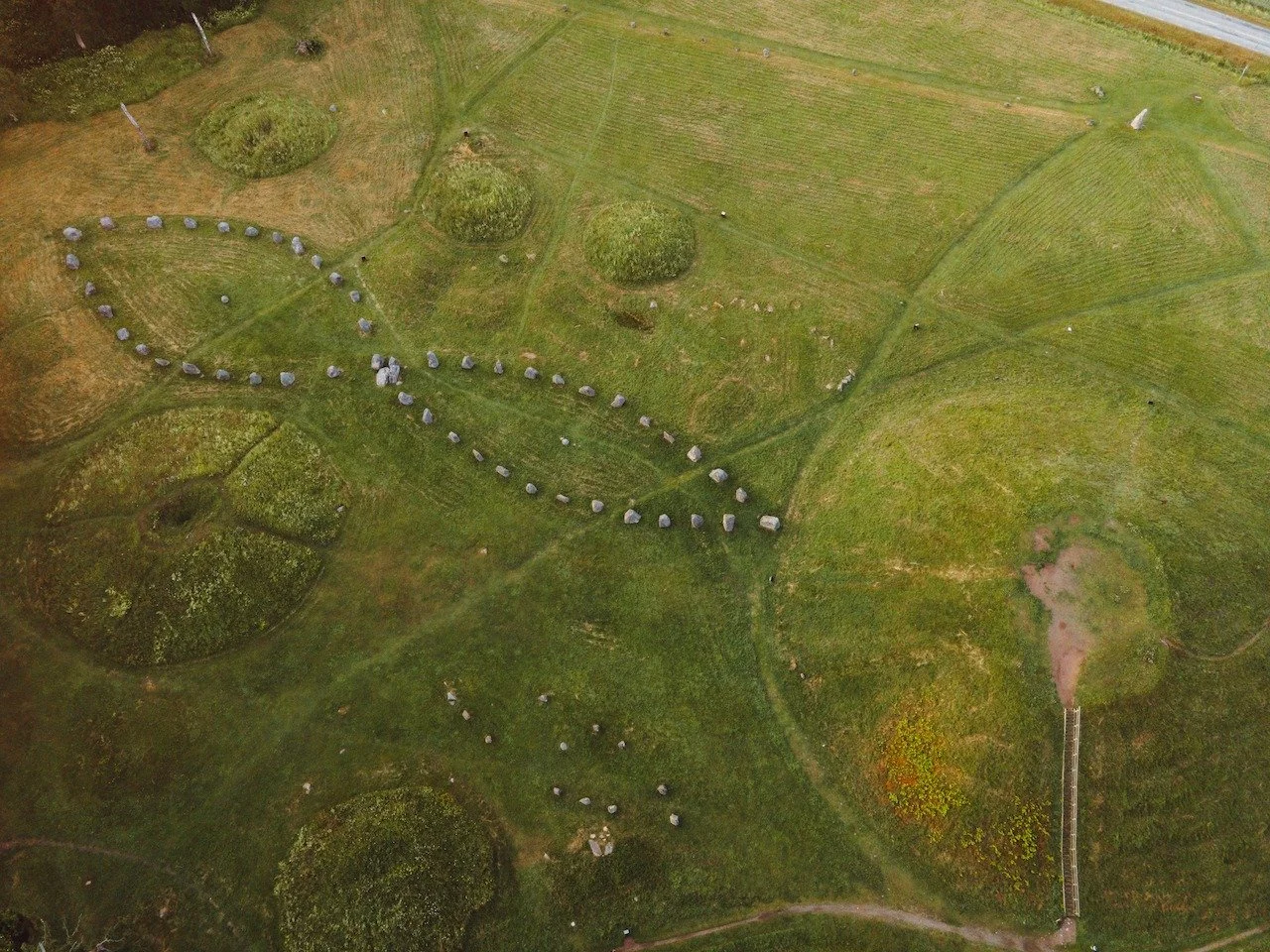 Golden hour over Anundsh&ouml;g, Sweden&rsquo;s largest burial mound, glowing softly in the evening light.
The ancient stone ships and earthworks form patterns shaped by rituals more than a thousand years ago.
Seen from above, history reveals itself 