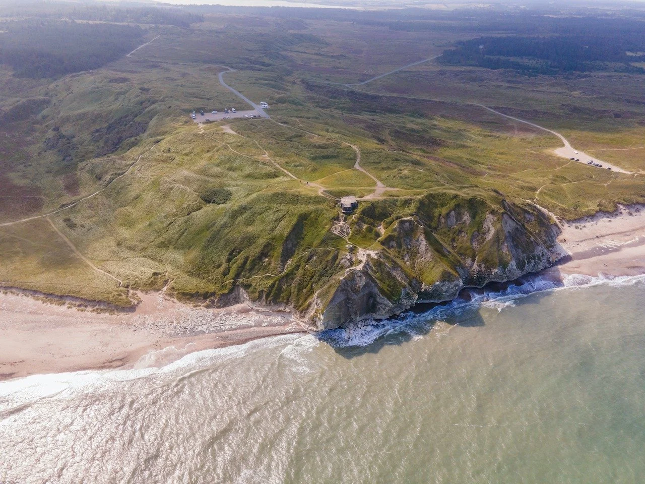 Bulbjerg rises abruptly from the Danish coastline, where limestone cliffs meet the endless North Sea.
This remote headland feels wild and untouched, shaped by wind, waves, and isolation rather than people.
From above, its rugged edges and open horizo