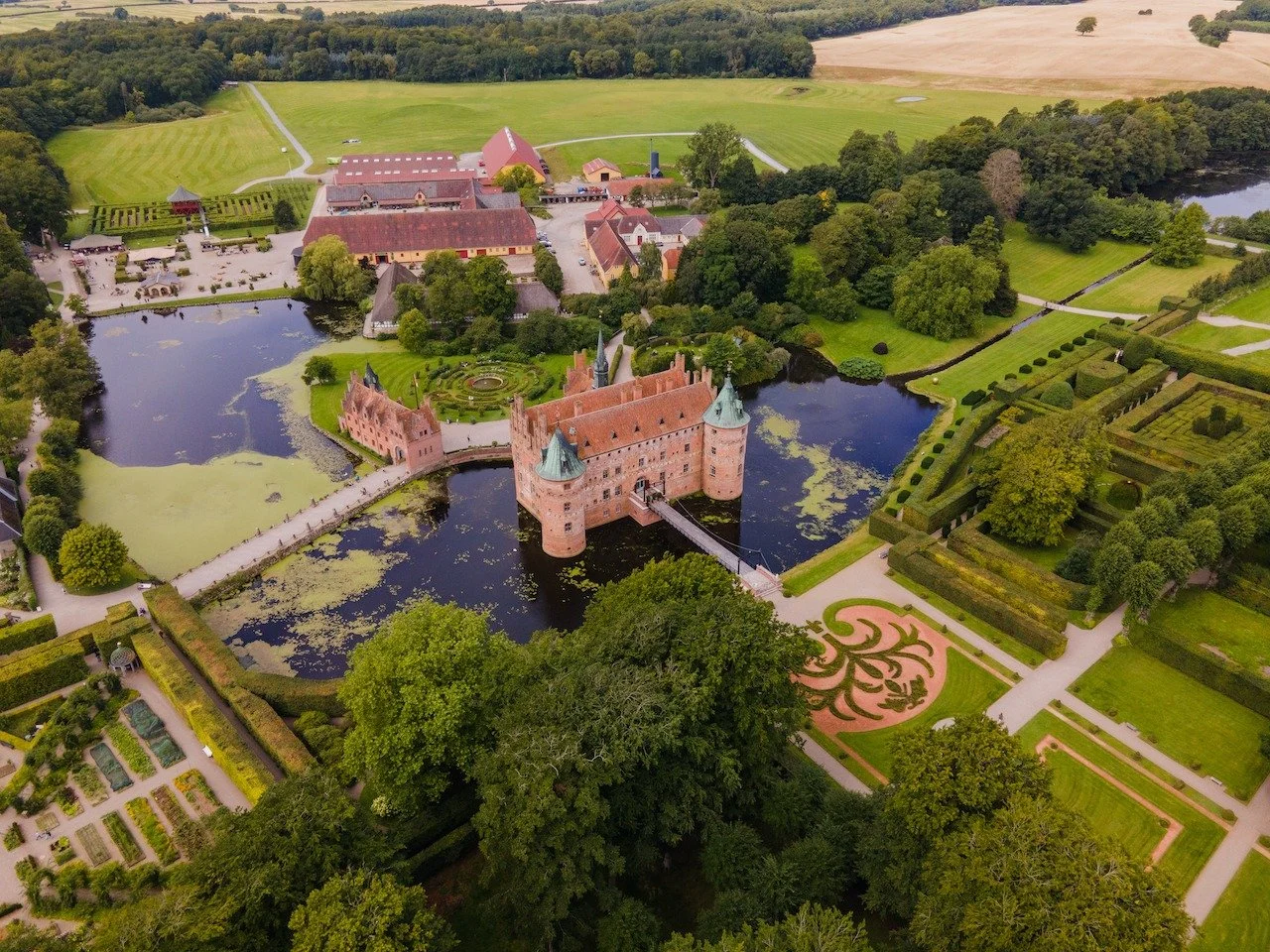 Egeskov Castle rises from the water like something out of a fairytale, perfectly preserved and impossibly elegant. Its red brick towers, surrounded by gardens and moats, showcase one of Europe&rsquo;s finest Renaissance castles. From the air, the har