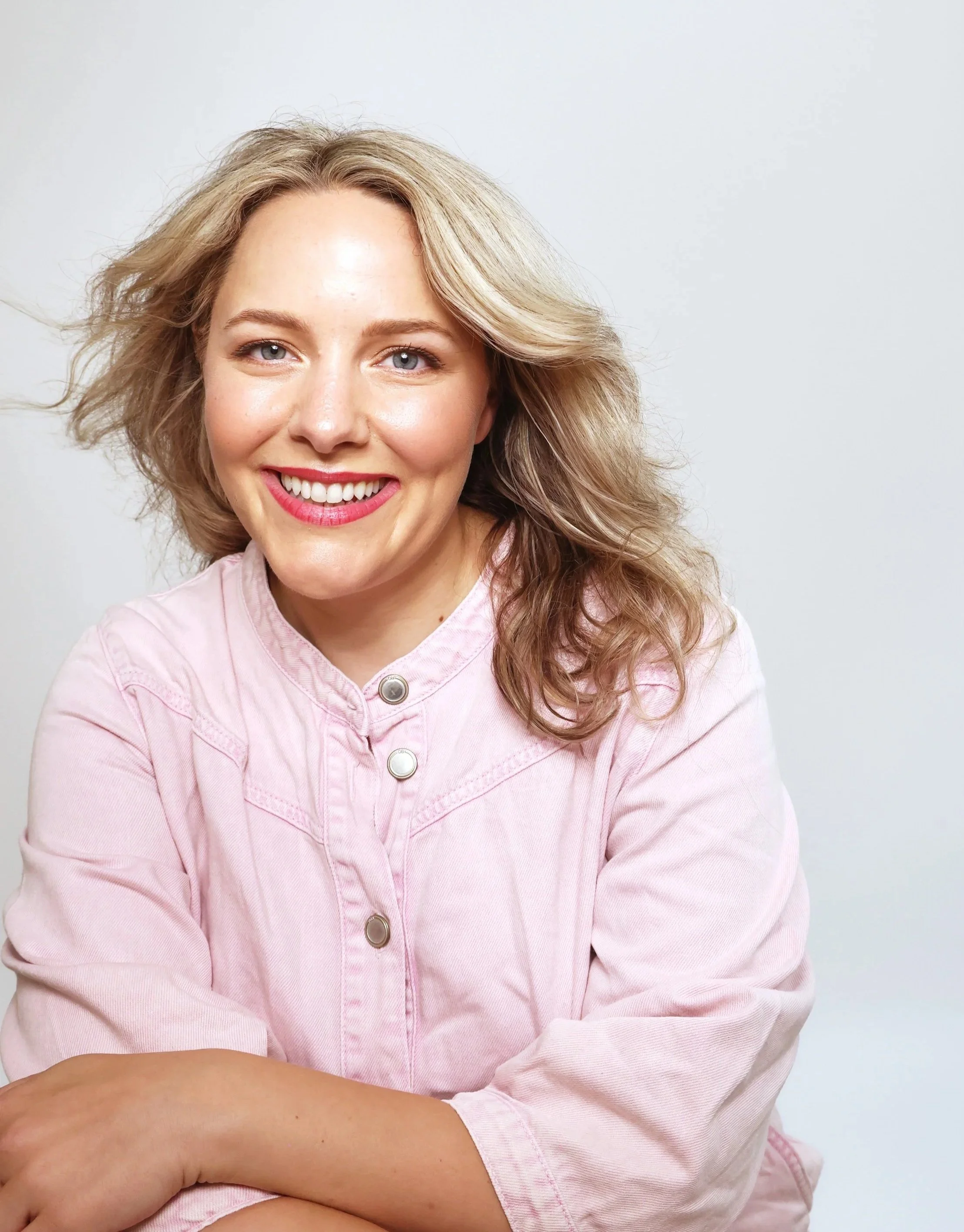 I’m Ettie, a white woman with dark blonde hair. I’m wearing a light pink shirt and smiling towards the camera.