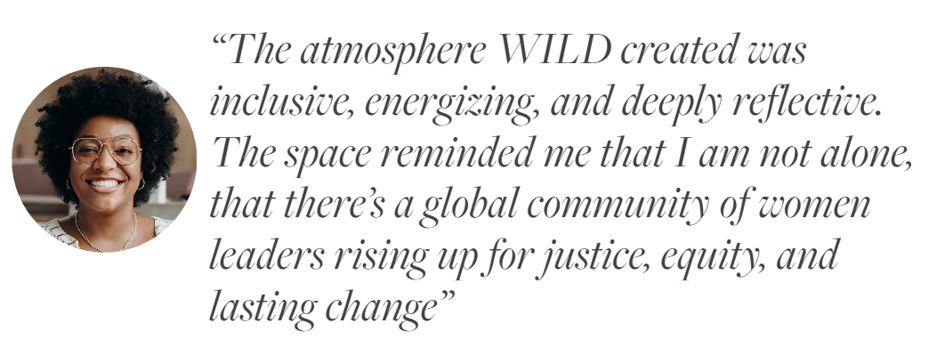 Close-up of a smiling woman with glasses and curly afro hair, wearing a light-colored top, on a white background with a quote about the atmosphere being inclusive, energizing, reflective, and connected to a global community of women leaders for justice and change.