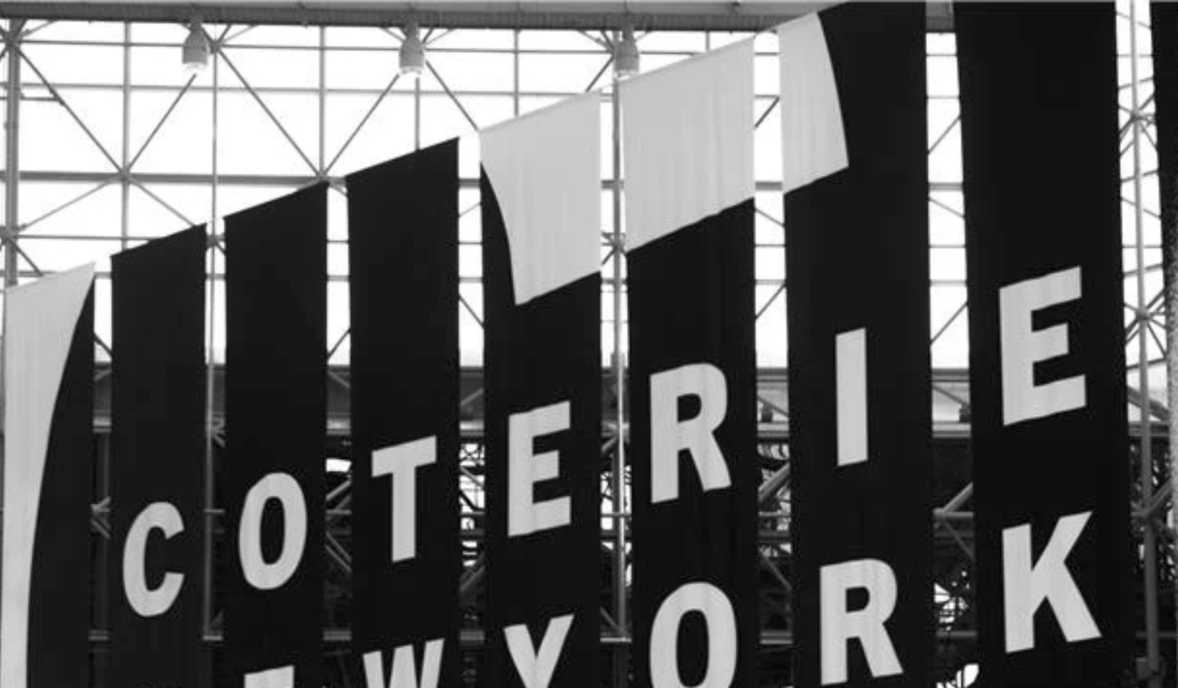 Black and white advertisement featuring a woman with short hair, wearing earrings and a black top, with overlaid white text promoting Coterie New York and its connection to fashion and innovation.