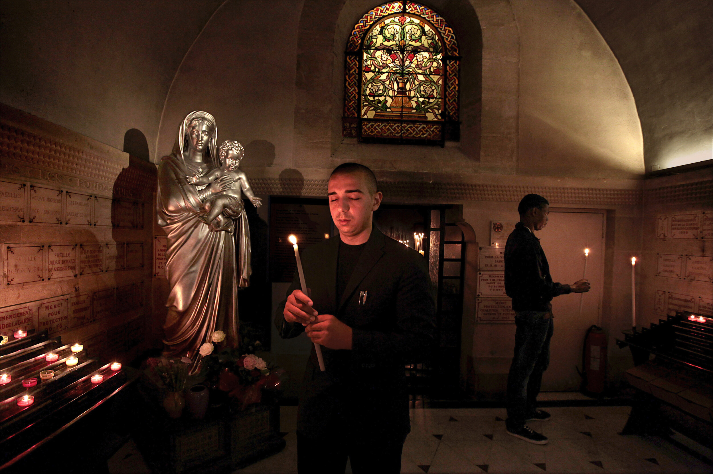   France. Marseille. 2014. Sylvain Massoudi, 25, lights a candle at the Notre Dame de la Garde. Sylvain, an Iranian immigrant, lives in Marseille but had never been to the world famous basilica before.  