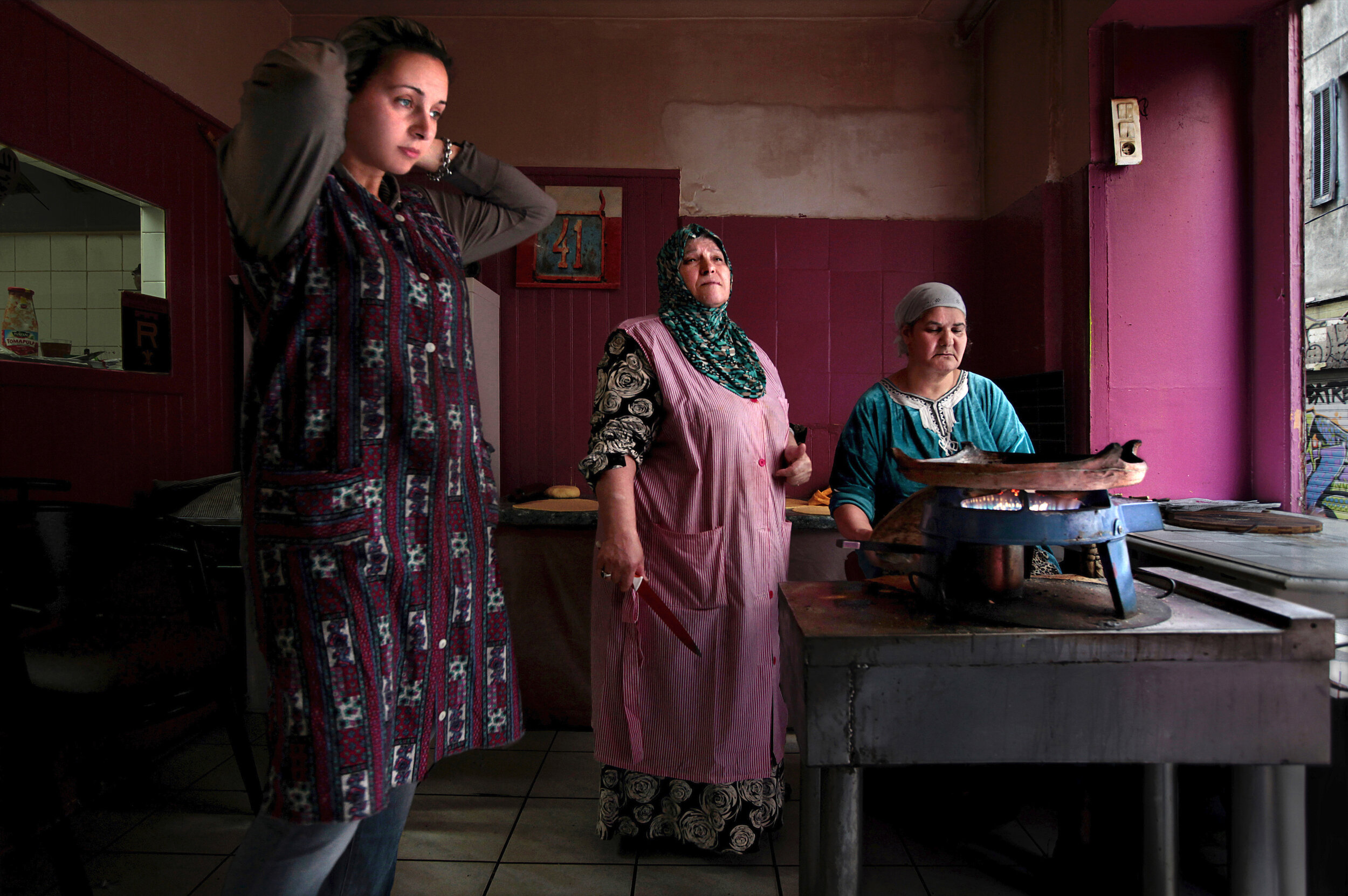   France. Marseille. 2014. Women prepare the traditional Algerian flatbread, Kesra, inside a shop at Noailles. Noailles is a neighborhood in the 1st arrondissement of Marseille located downtown near the Old Port. Noailles is famous for its old buildi