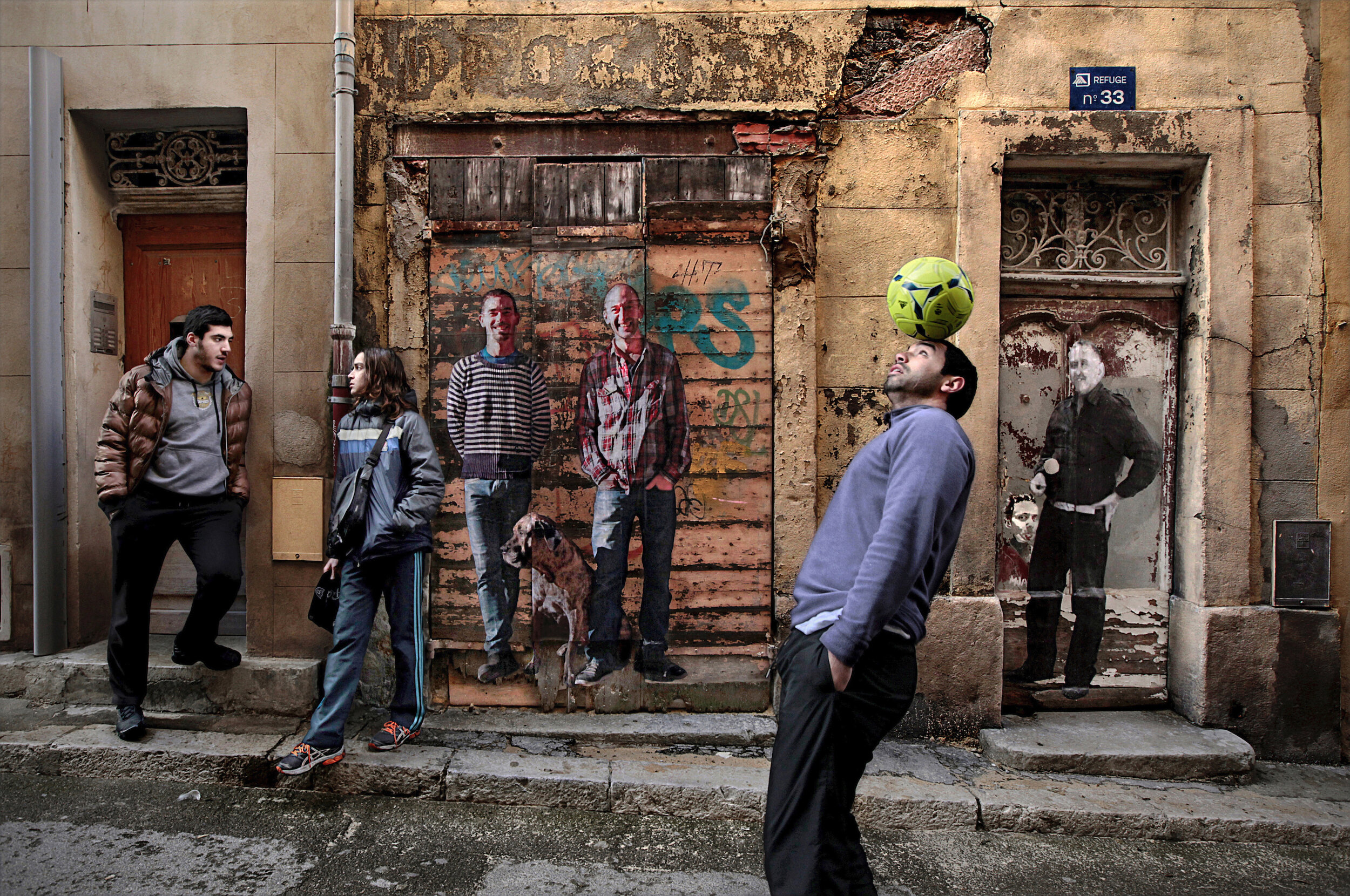   France. Marseille. 2013. A young man tries to impress with his soccer skills on a street in Le Panier district. Le Panier, the oldest part of Marseille, is where the Greeks first settled and founded the city of Massalia some 2600 years ago. Since t