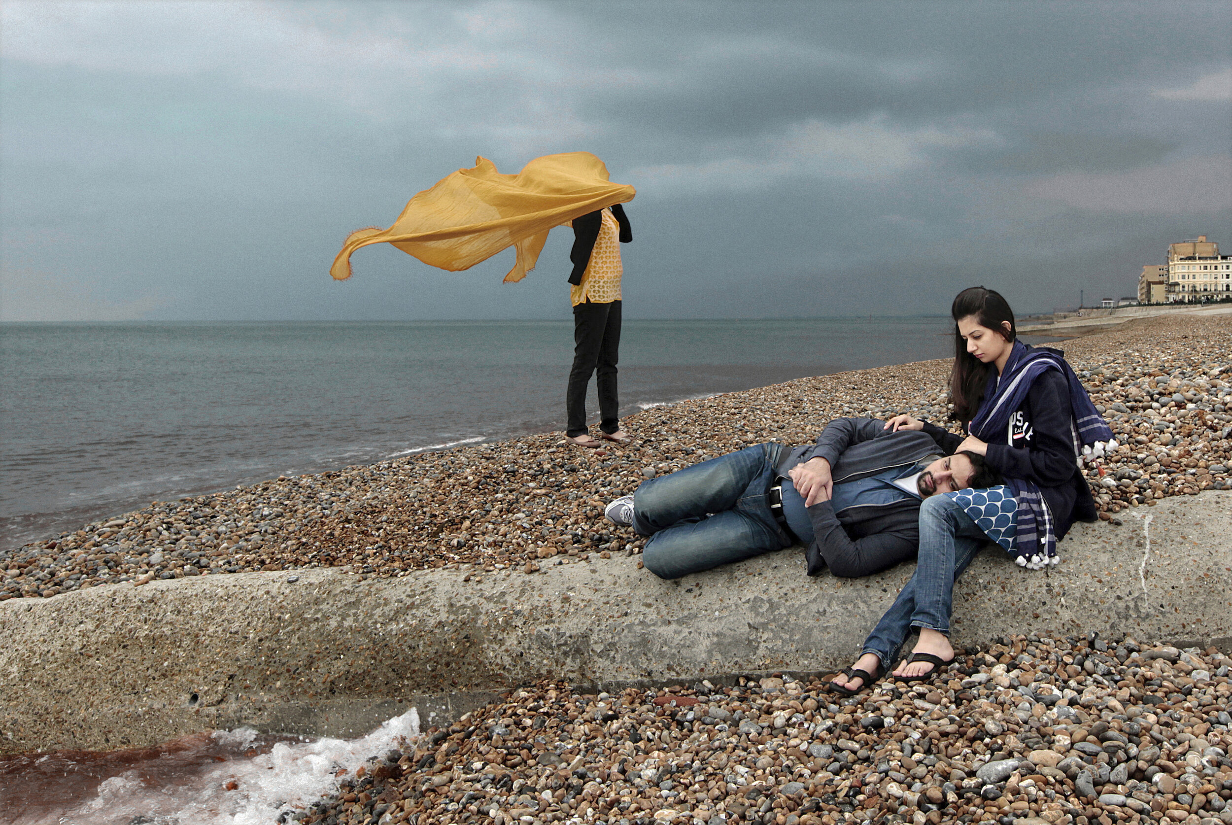   UK. Brighton. 2012. Rida Awan [right] and her husband, Omar, share a quiet moment at the Brighton beach on a cloudy Sunday afternoon.        