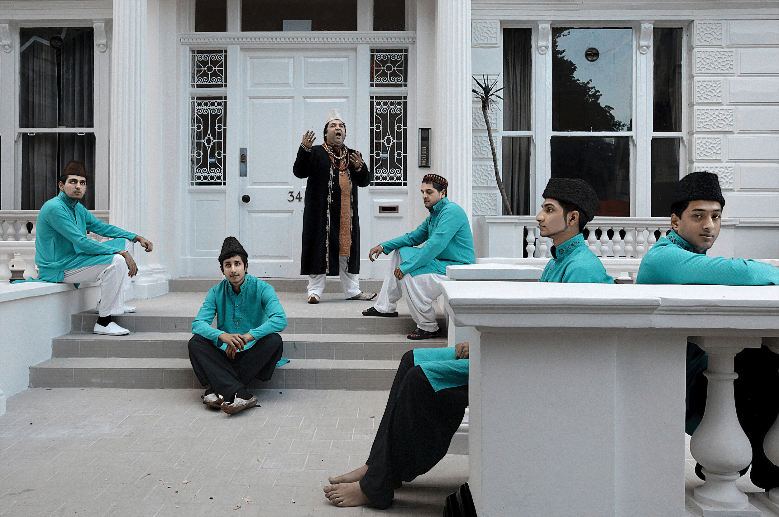   UK. London. 2011. Ustad Hajji Ameer Khan [standing] says a prayer before he and his team leaves for a musical performance. Khan is a Qawwal, a Sufi devotional musician.        