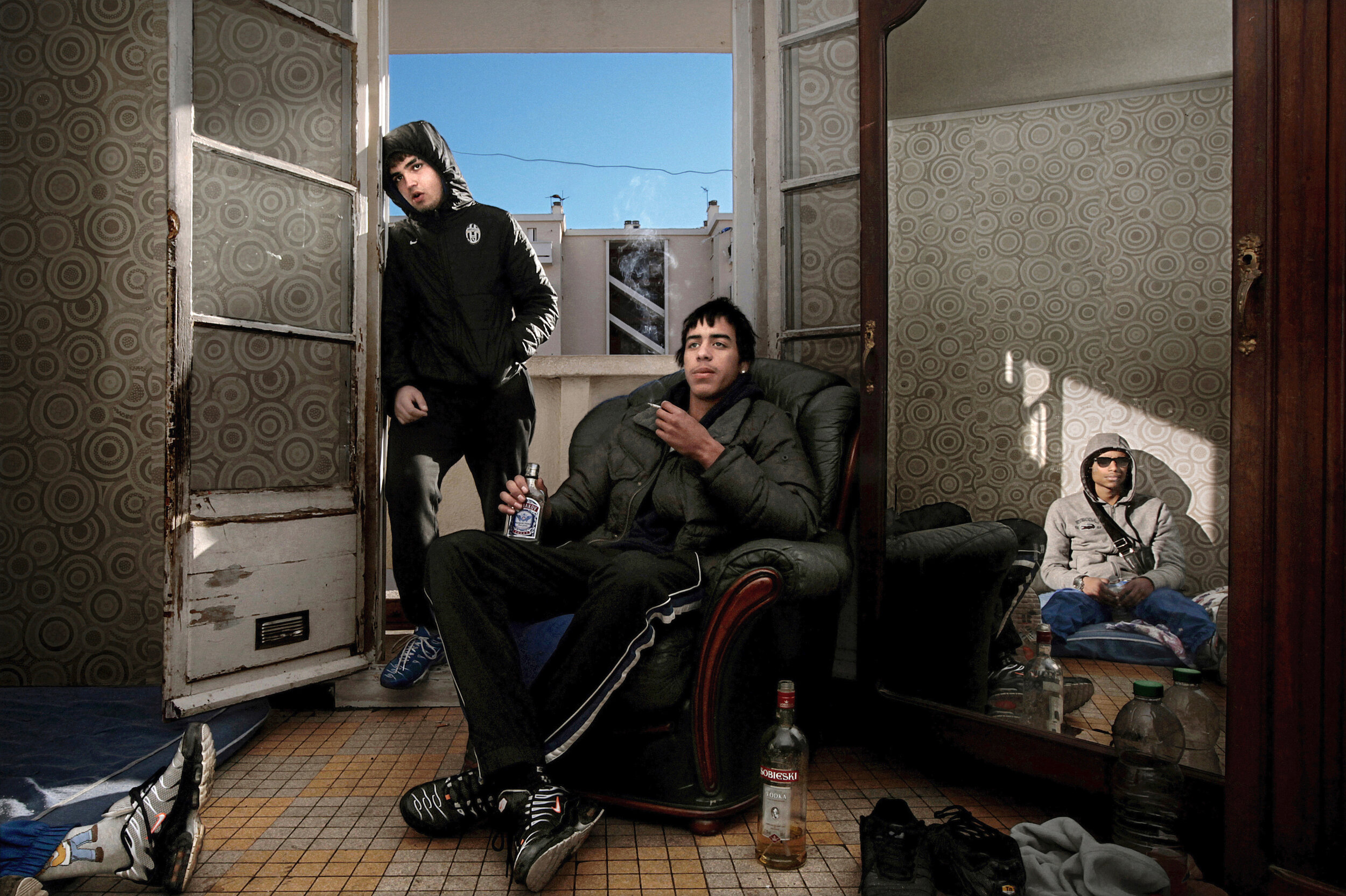   France. Marseille. 2013. Squatting in a social housing apartment, young men watch a soccer match on TV.        