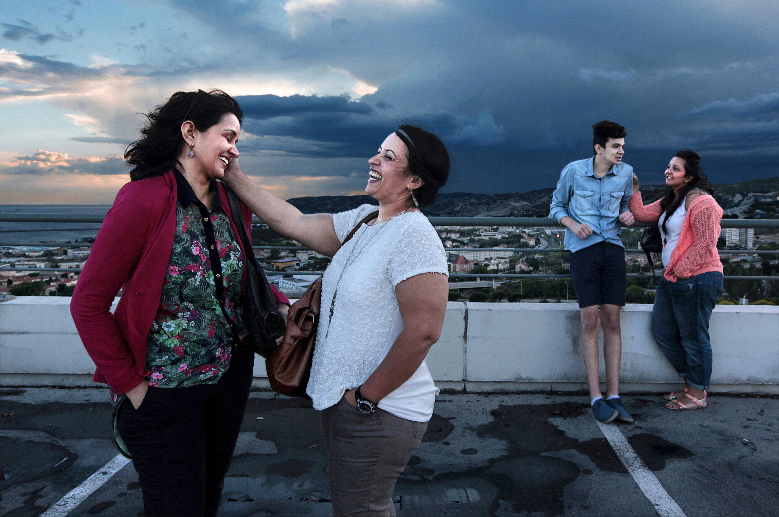   France. Marseille. 2014. Sisters share a joke outside The Grand Littoral shopping center.        