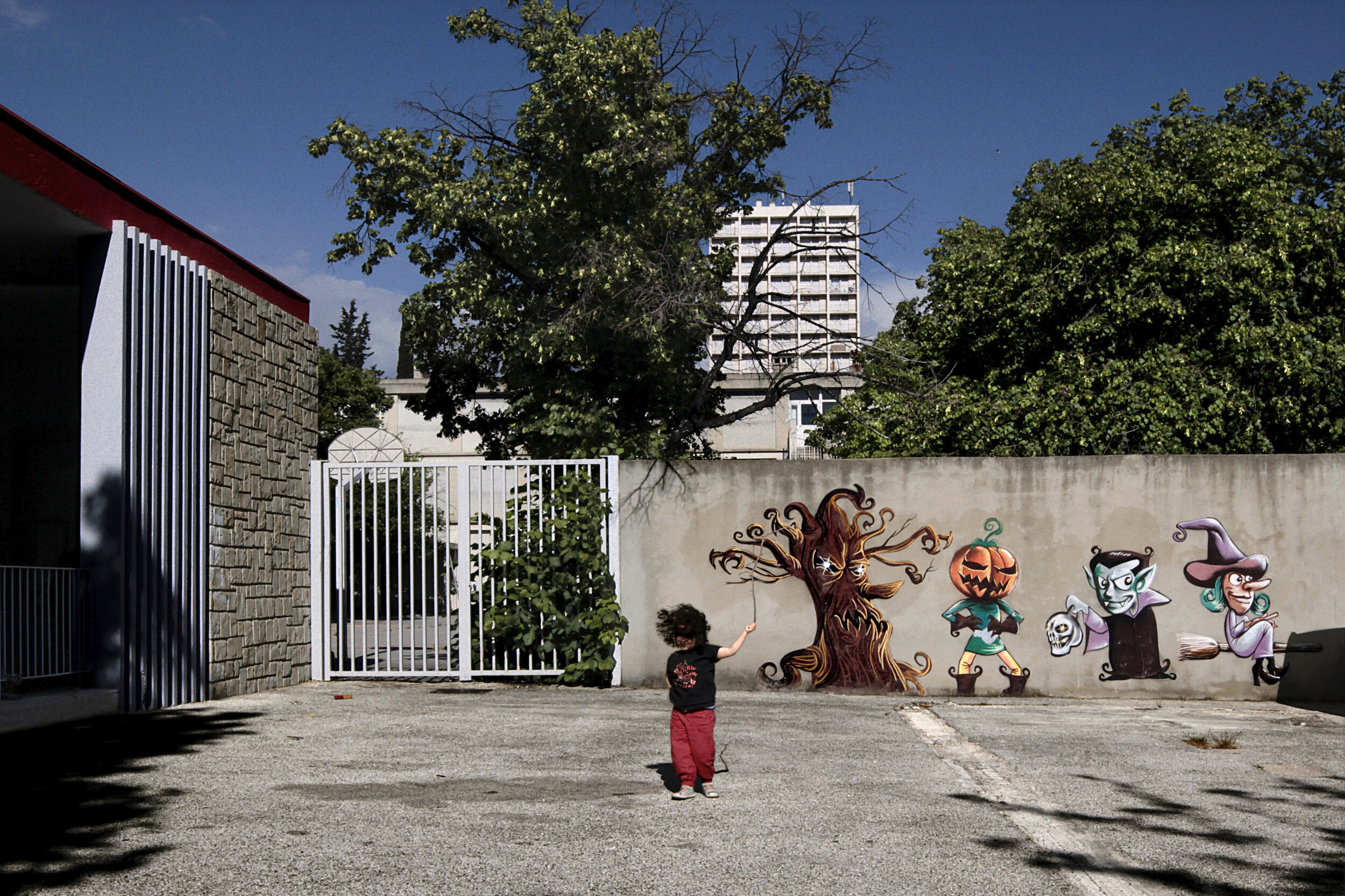   France. Marseille. 2014. A child plays in the courtyard of Agora Centre, a social development organization located in quartier Busserine, 14th arrondissement of Marseille. For a number of reasons, including high crime and violence, Busserine and ne