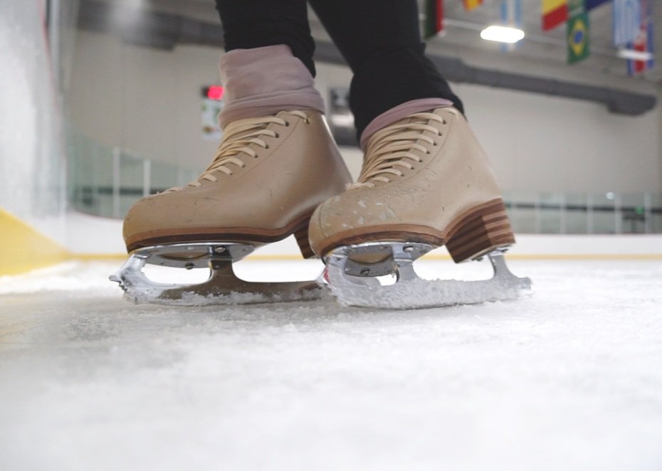 Close-up of a person wearing beige ice skates on an ice rink.