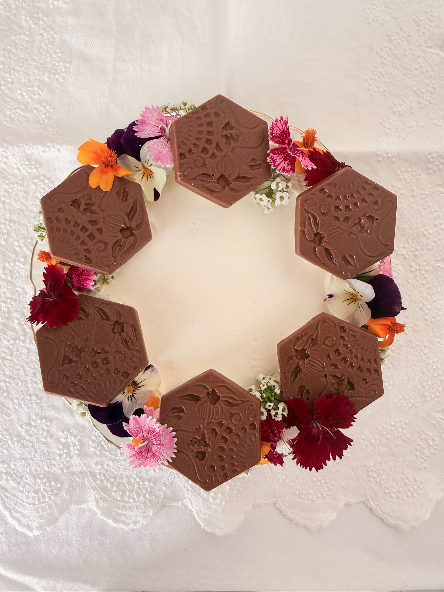 Pastel blanco con flores y panots del Paseo de Gràcia hechos con chocolate