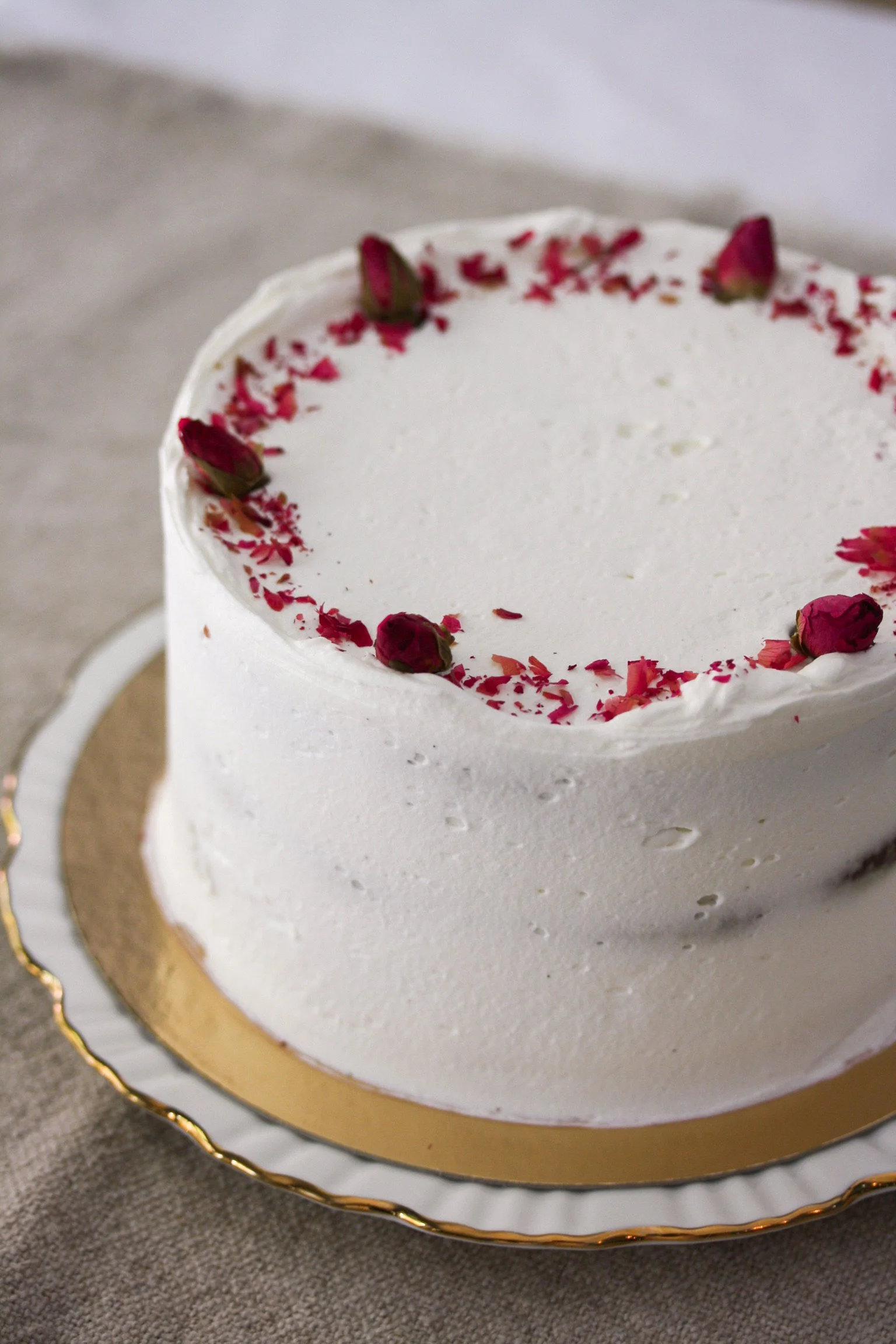 Two-layer chocolate cake with vanilla frosting and pink rosebuds on top.