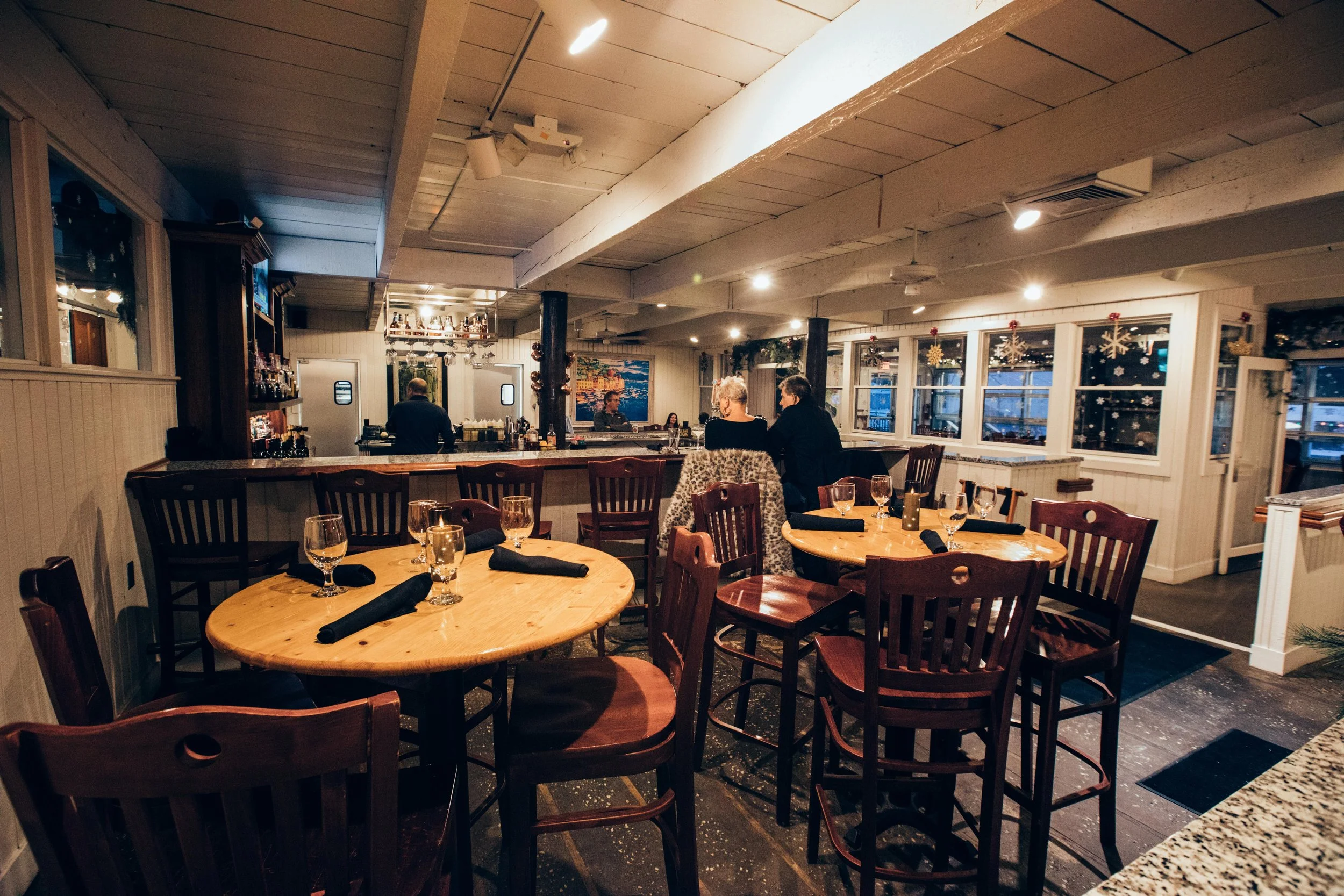 Guests gathered around the warm wooden bar at Sandy Point Beach House