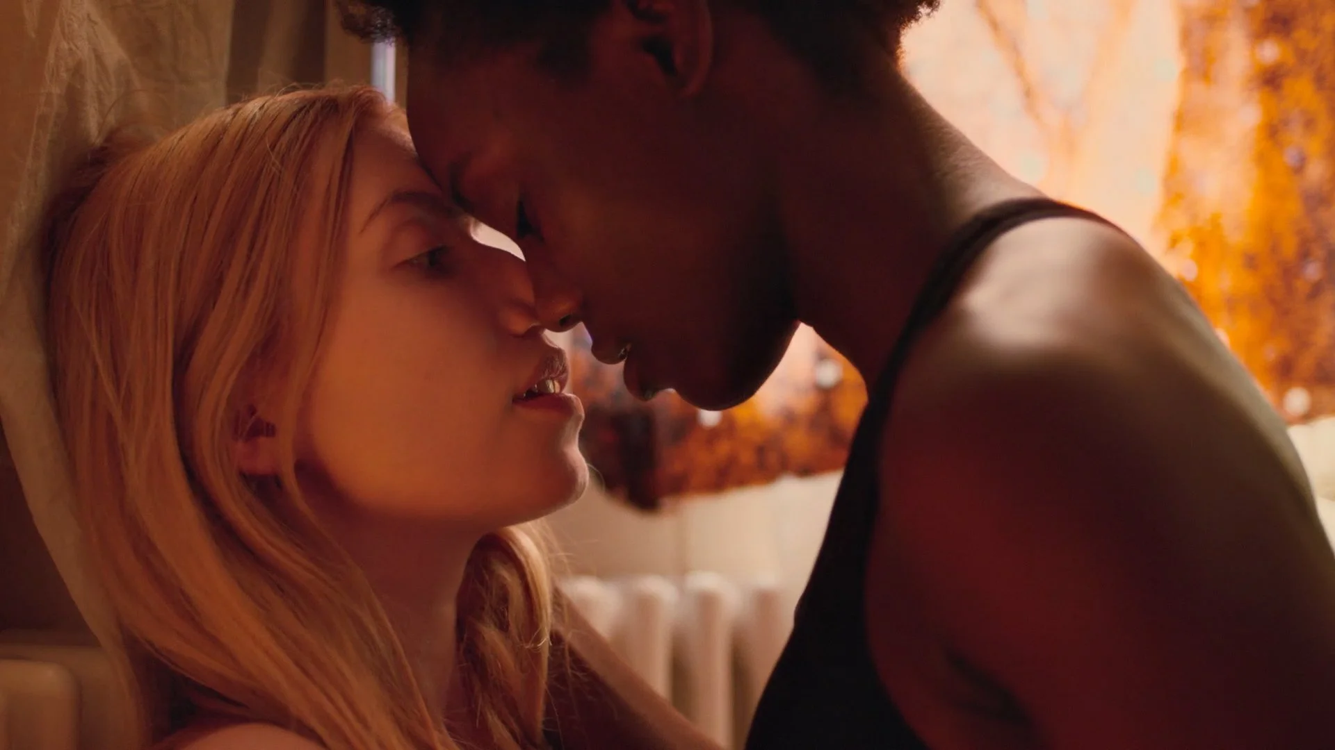 Two women with their foreheads touching, close-up, intimate moment, warm lighting.