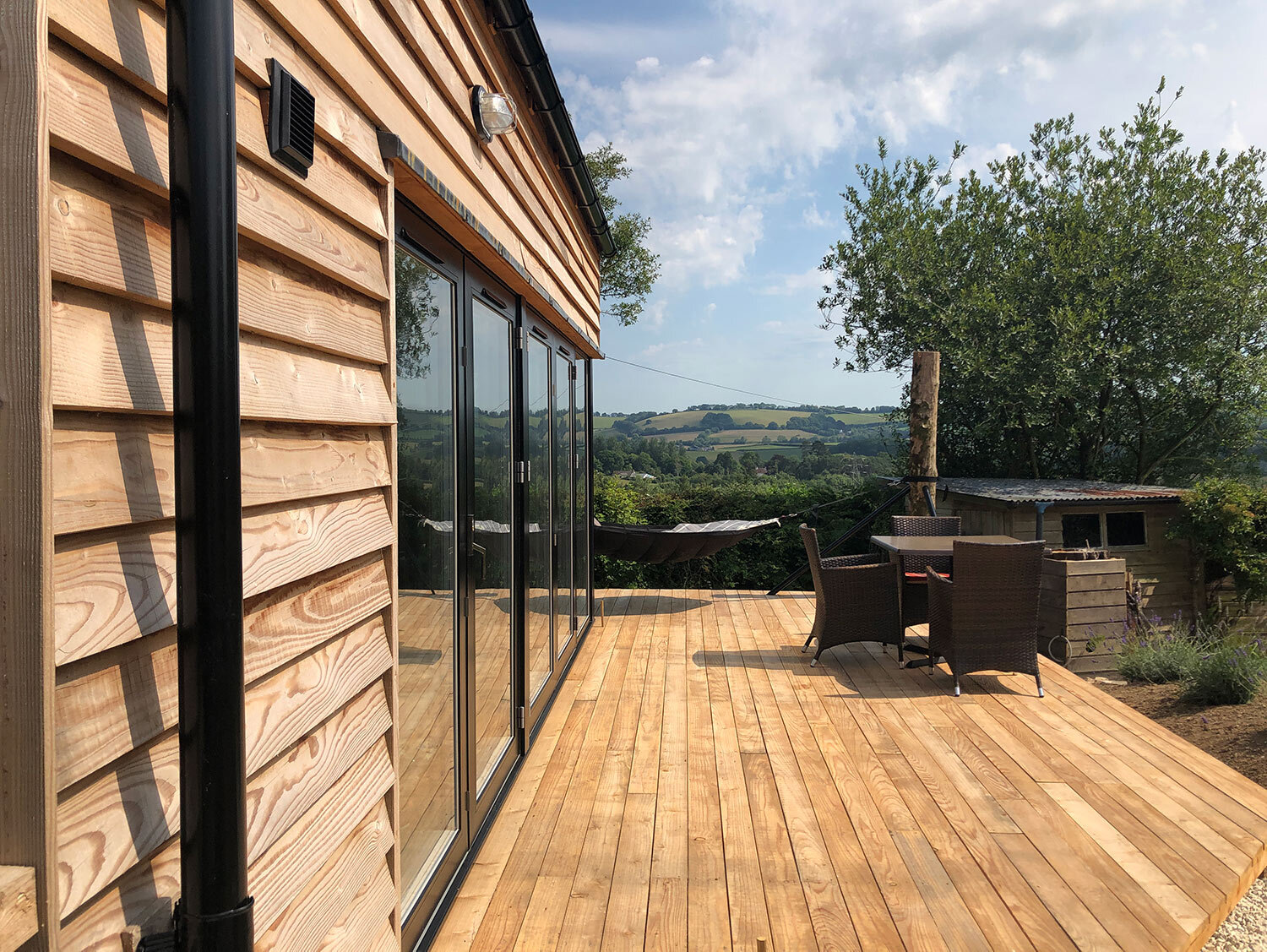 Large bifold doors opening onto timber deck with views over South Hams