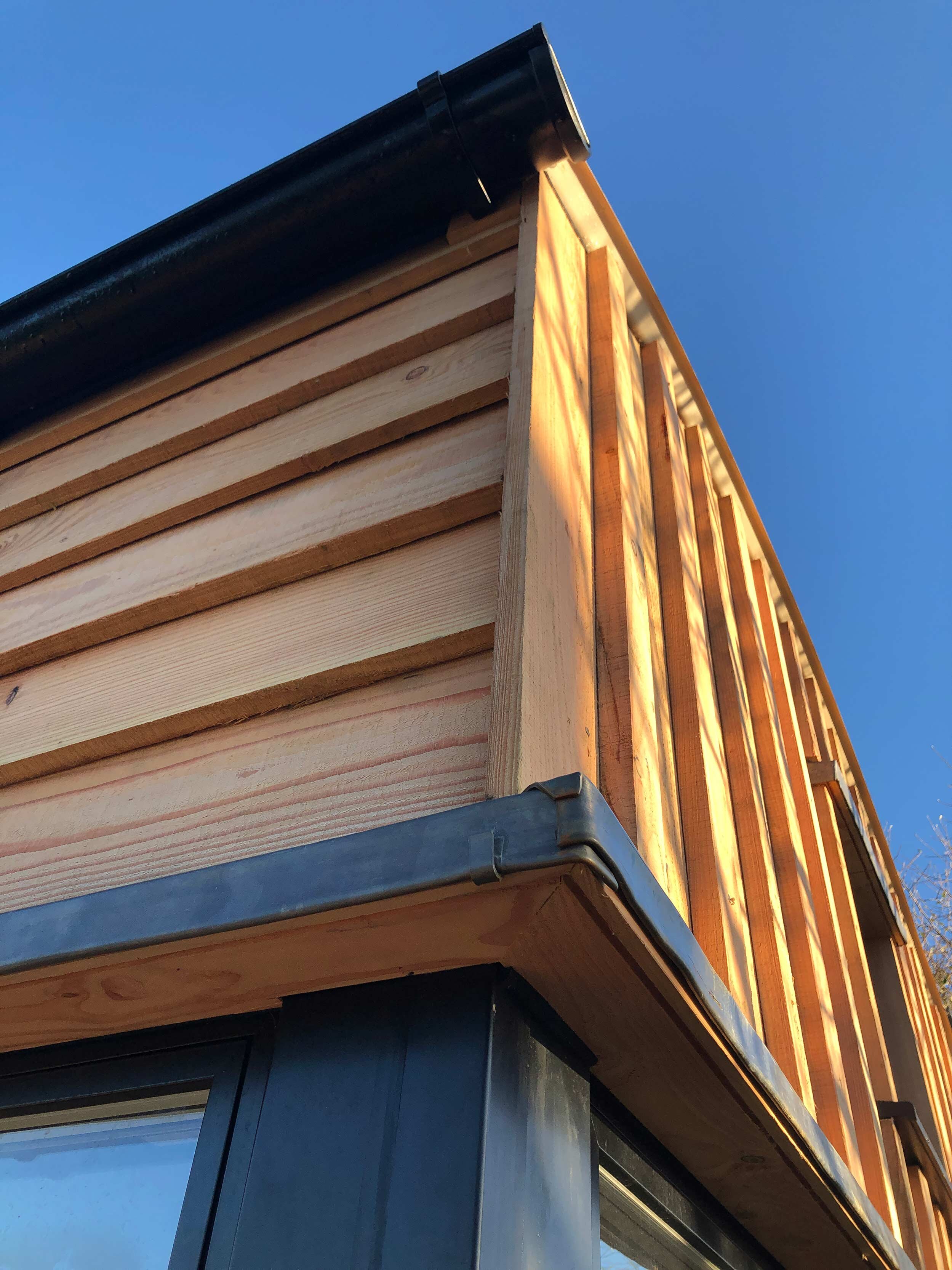 Detail of freshsawn Larch cladding and lead flashing over cabin glazing