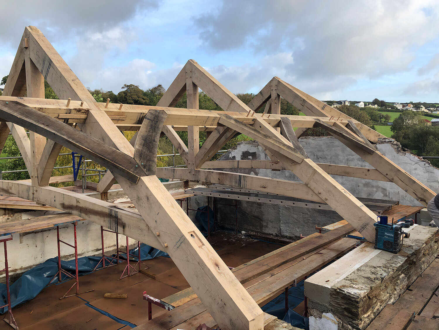 Pegged timber roof under construction on stone building
