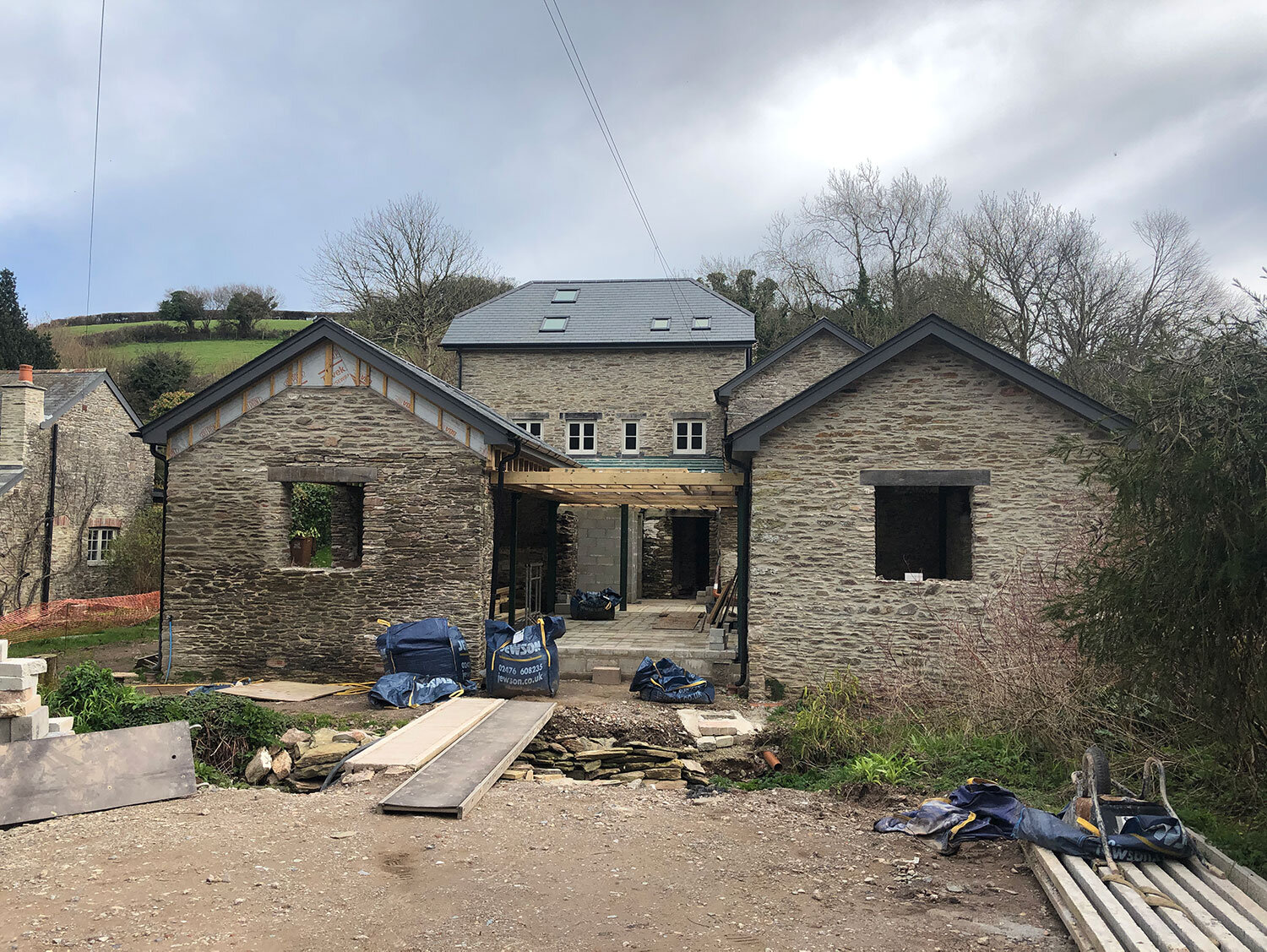 Green timber roof for two stone barns under construction