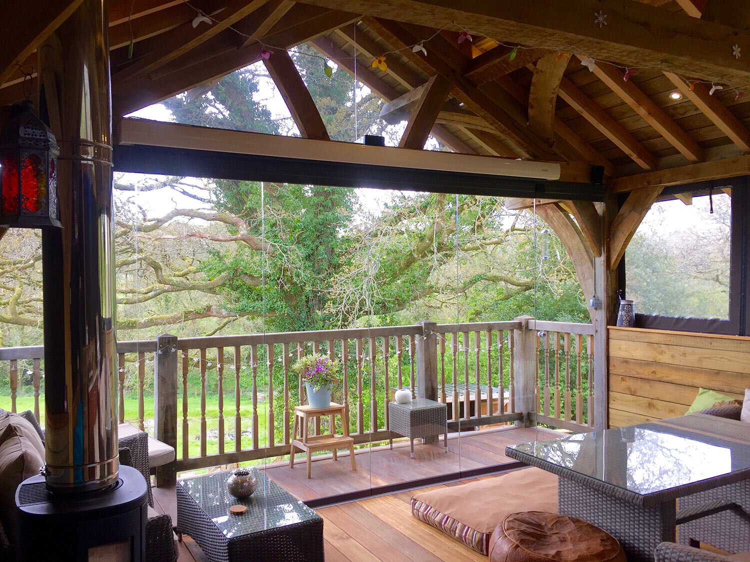 Outdoor-kitchen-on-stilts-with-glass-shutters-woodburner-in-devon-garden