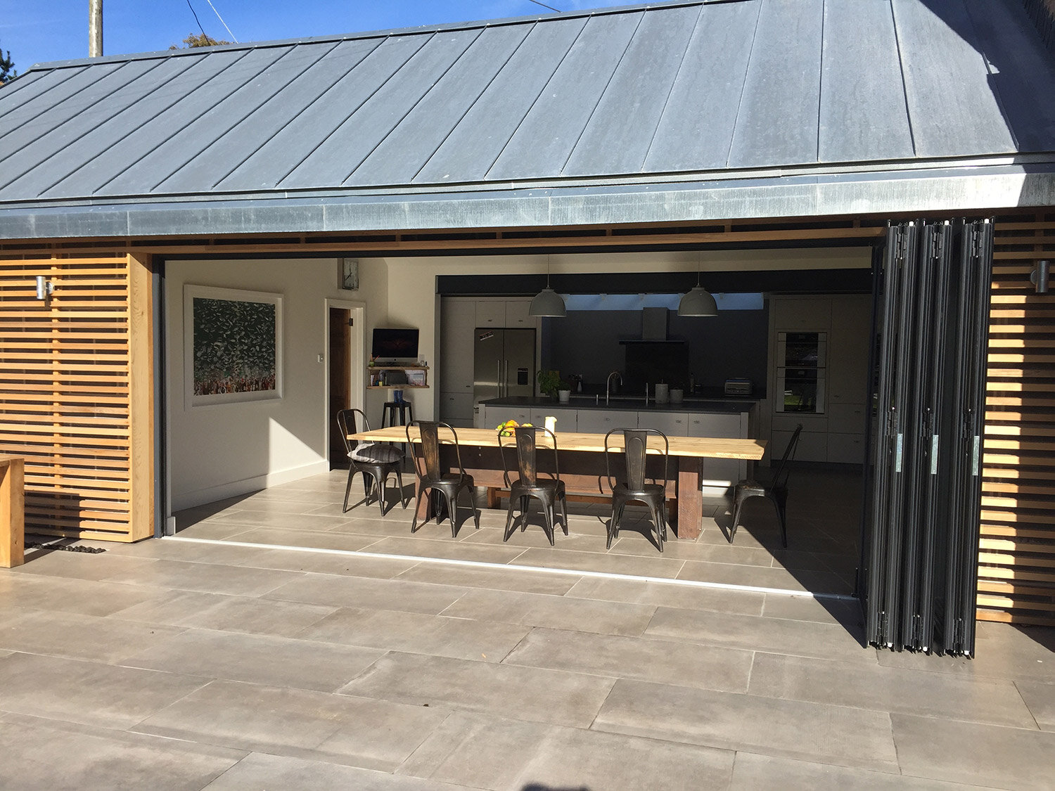 Timber annexe with zinc roof and huge bifold doors opening onto garden