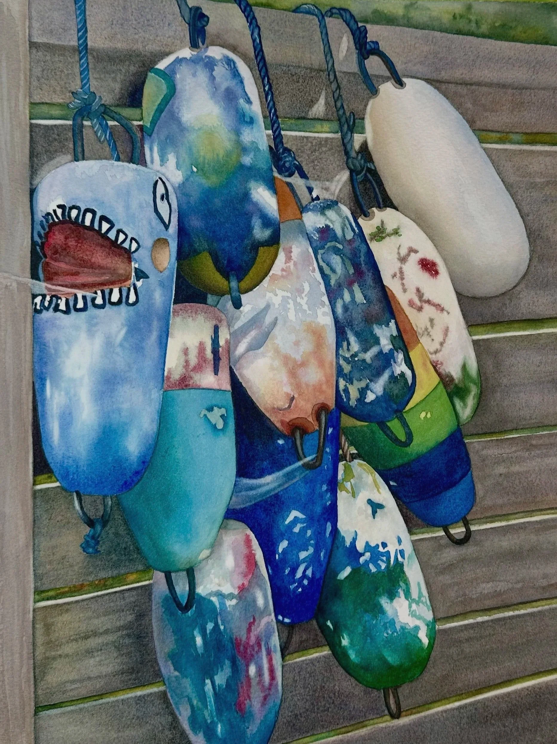 A group of colourful buoys hanging on a wooden fence