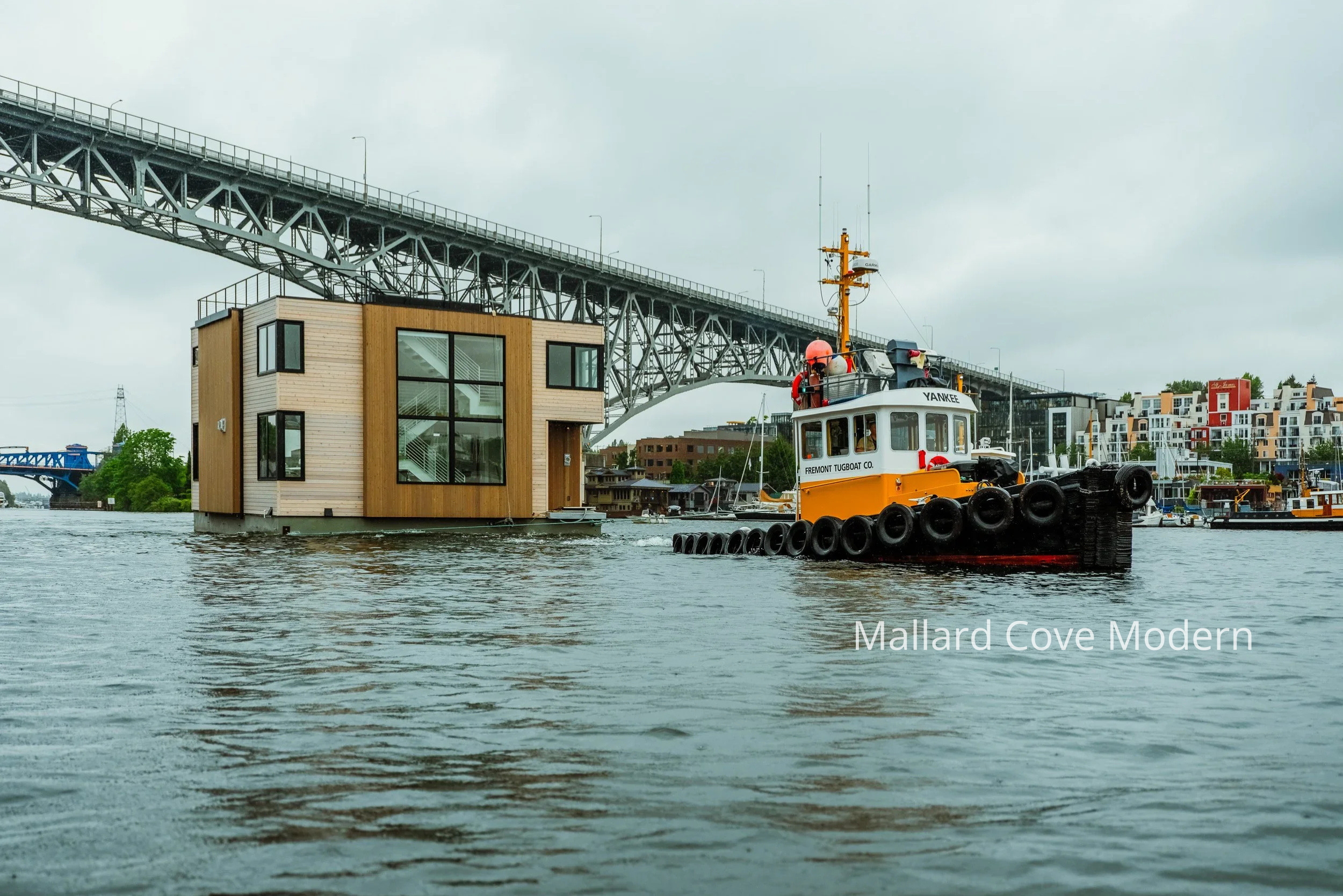 Lake Union modern floating home designed by ECCO Architecture in Seattle, featuring expansive floor-to-ceiling windows, sliding glass doors, and multiple outdoor living areas including a main-level deck, accessory float, and rooftop deck. This contem
