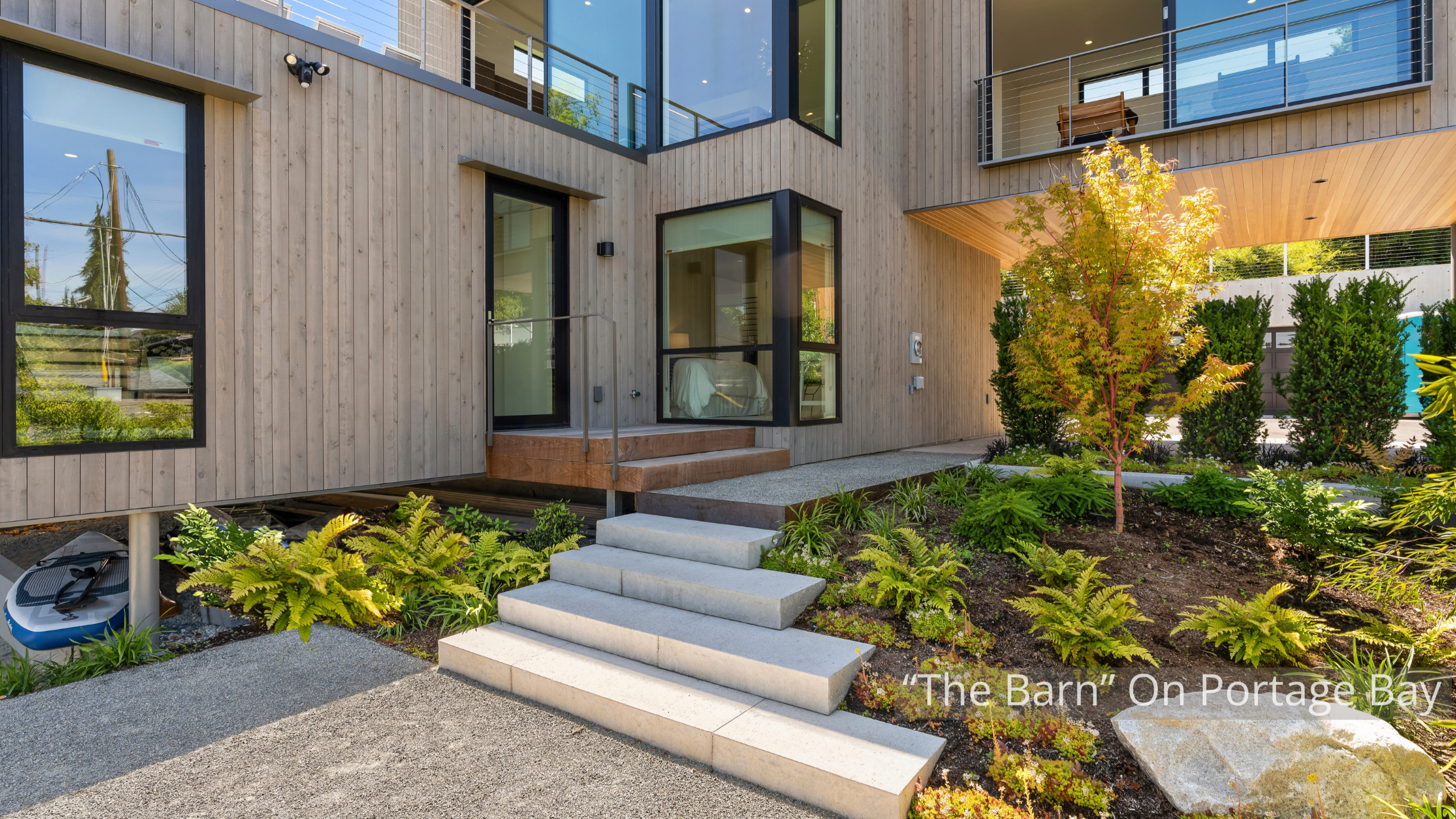 The "Barn" on Portage Bay is a contemporary waterfront residence defined by its dramatic gabled form, expansive floor-to-ceiling glass, and warm natural wood detailing. Large windows fill the home with natural light while connecting the interior to t