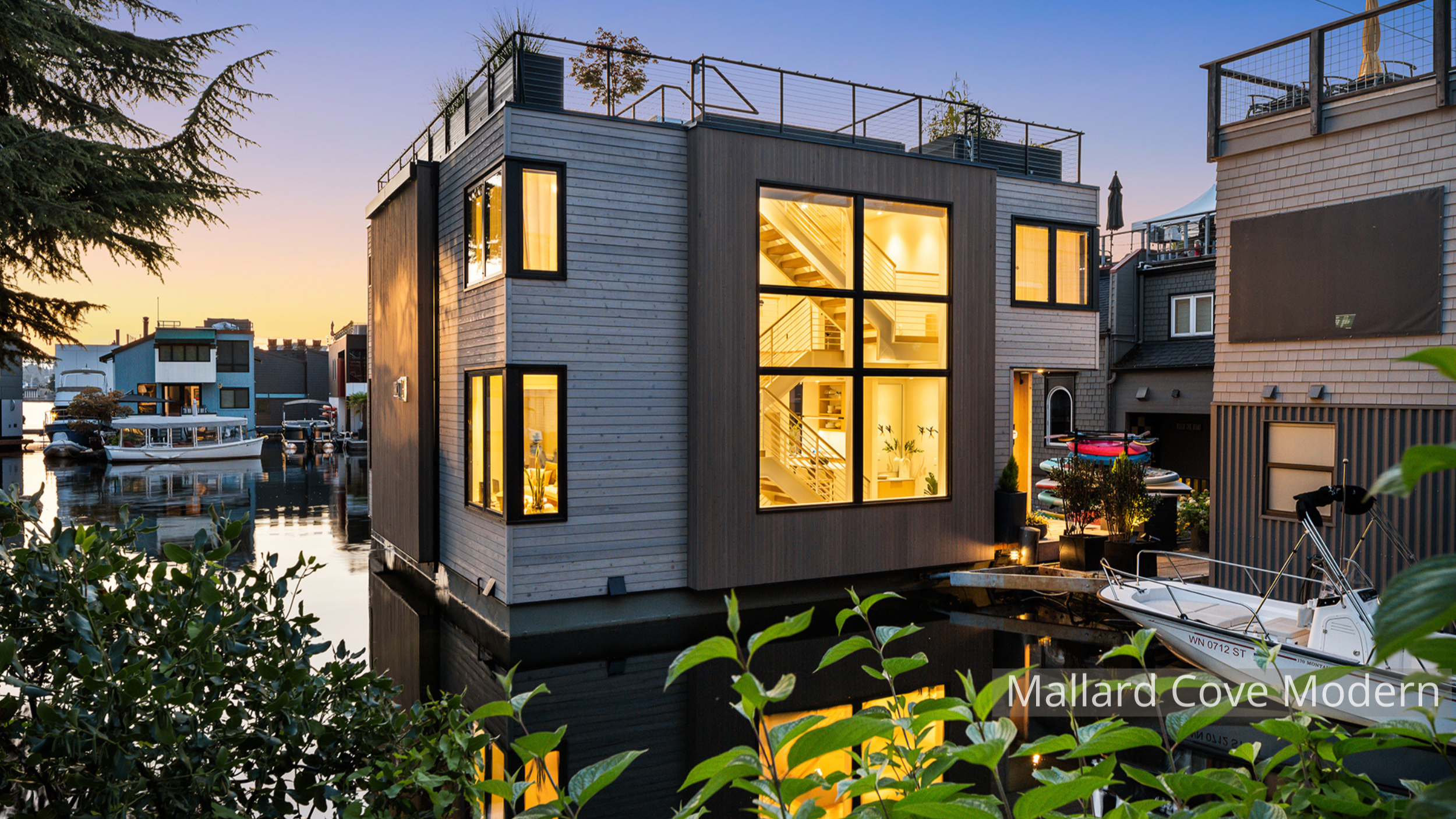 Lake Union modern floating home designed by ECCO Architecture in Seattle, featuring expansive floor-to-ceiling windows, sliding glass doors, and multiple outdoor living areas including a main-level deck, accessory float, and rooftop deck. This contem