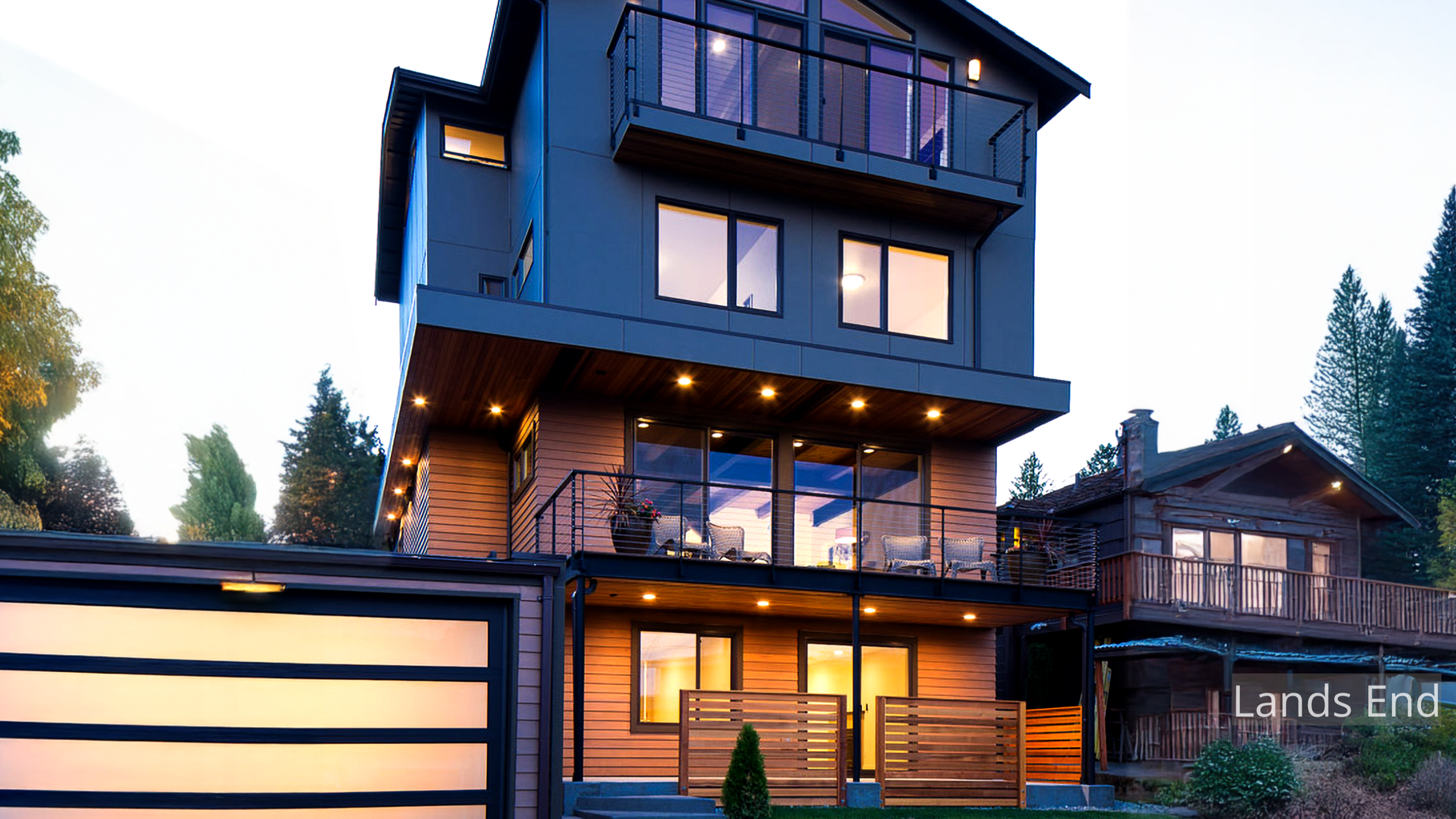 Evening view of the Lands End Remodel, a four-level modern home overlooking Salmon Bay. ECCO Architecture transformed a modest single-story structure into a contemporary residence featuring open-plan living, expansive glazing, and a top-floor master 