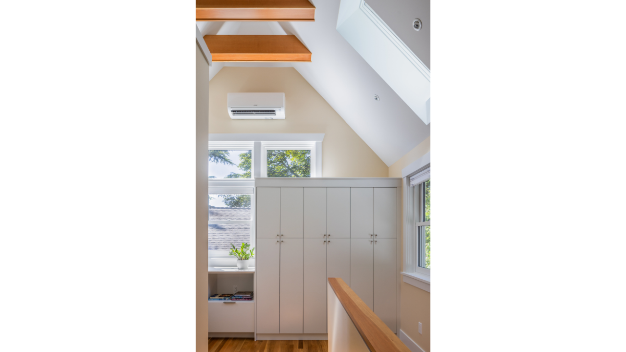 Upper-level interior of a Seattle DADU featuring a vaulted ceiling, exposed wood beams, and built-in storage cabinetry. Natural light enters through multiple windows, enhancing the sense of openness within the compact footprint. This accessory dwelli