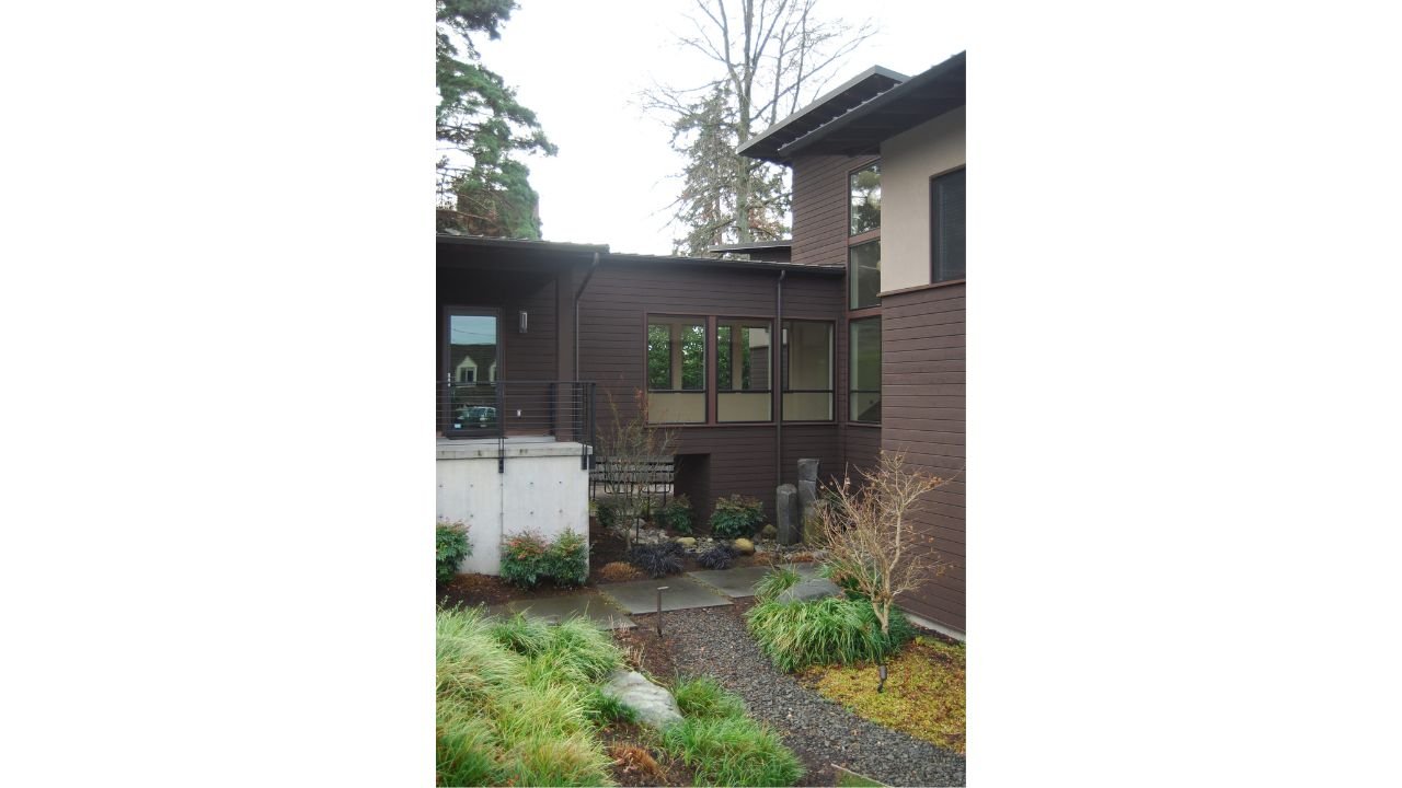 A sheltered courtyard between the wings of the Lake Washington New Home is filled with layered plantings, stone paths, and intimate garden views. The landscaped space brings nature into the center of the residence and softens the home’s clean contemp