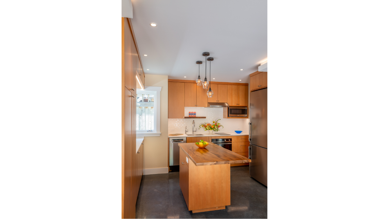 Compact kitchen design within a Seattle DADU featuring warm wood cabinetry, a mobile island, and efficient small-space layout. The kitchen is designed for flexibility, allowing the island to adapt for cooking, dining, or additional workspace. Clean l