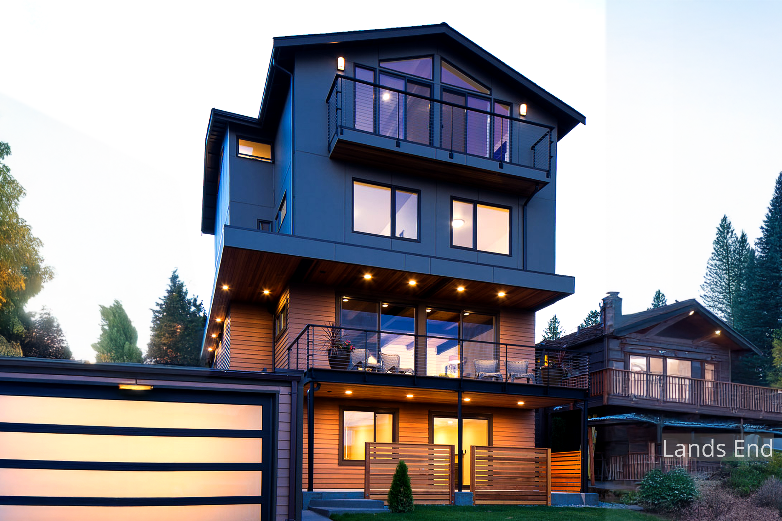 Evening view of the Lands End Remodel, a four-level modern home overlooking Salmon Bay. ECCO Architecture transformed a modest single-story structure into a contemporary residence featuring open-plan living, expansive glazing, and a top-floor master 