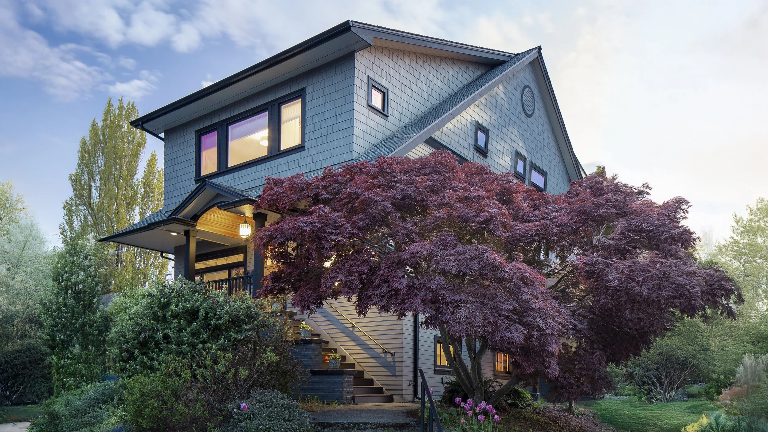 Pacific Northwest Craftsman home with blue cedar shingle siding, covered porch, and mature Japanese maple in front garden