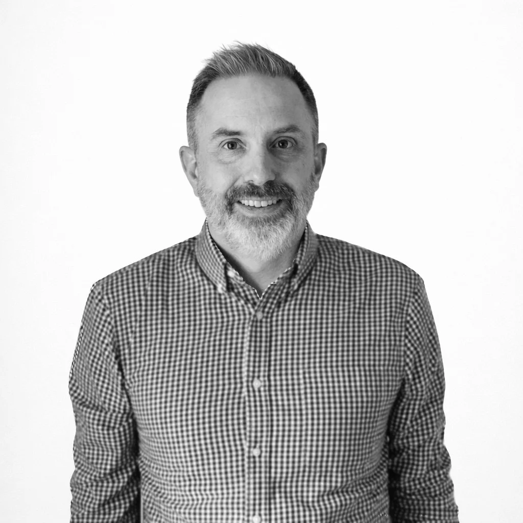 Black and white portrait of Evan Wehr smiling at the camera against a plain white background.