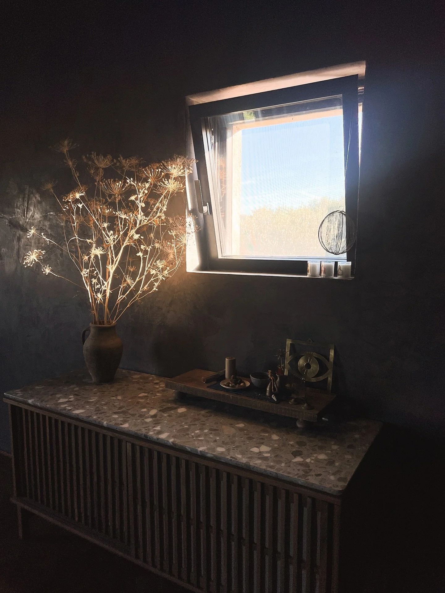 Continuing with the studio feature, this is my little meditation area where I keep some special objects and reminders. I love the light coming in this small window past the dried branches and the marble terrazzo sideboard top. It&rsquo;s a nice spot 