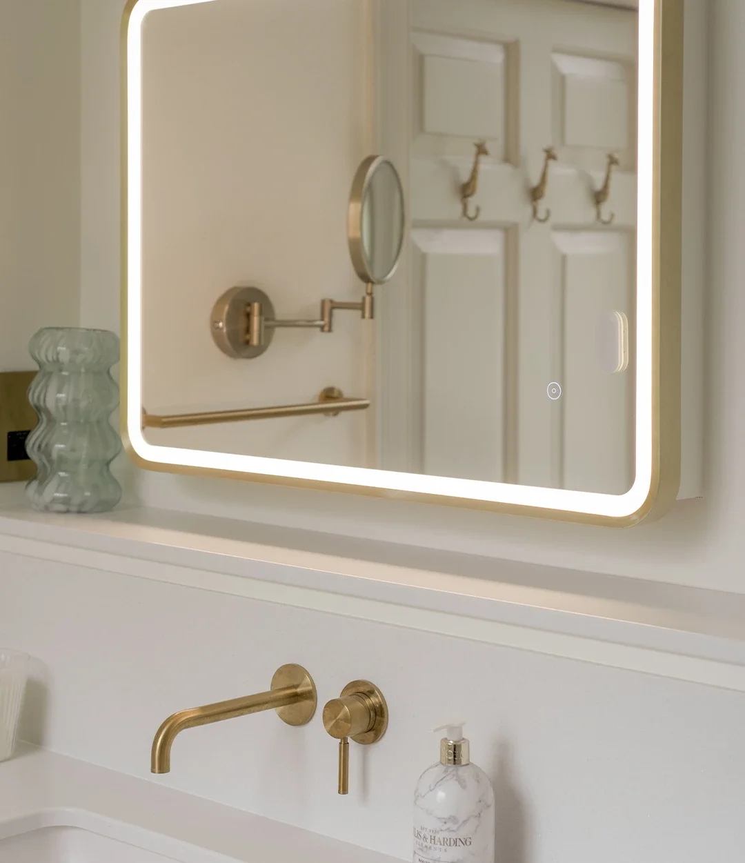 Bathroom vanity area with forward-set brass mirror, quartz surface and brass tapware