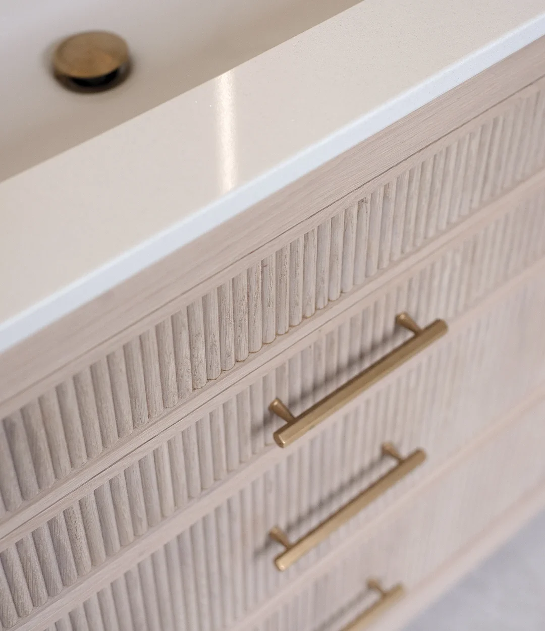 Bespoke white oak fluted bathroom vanity with quartz worktop and brushed brass handles
