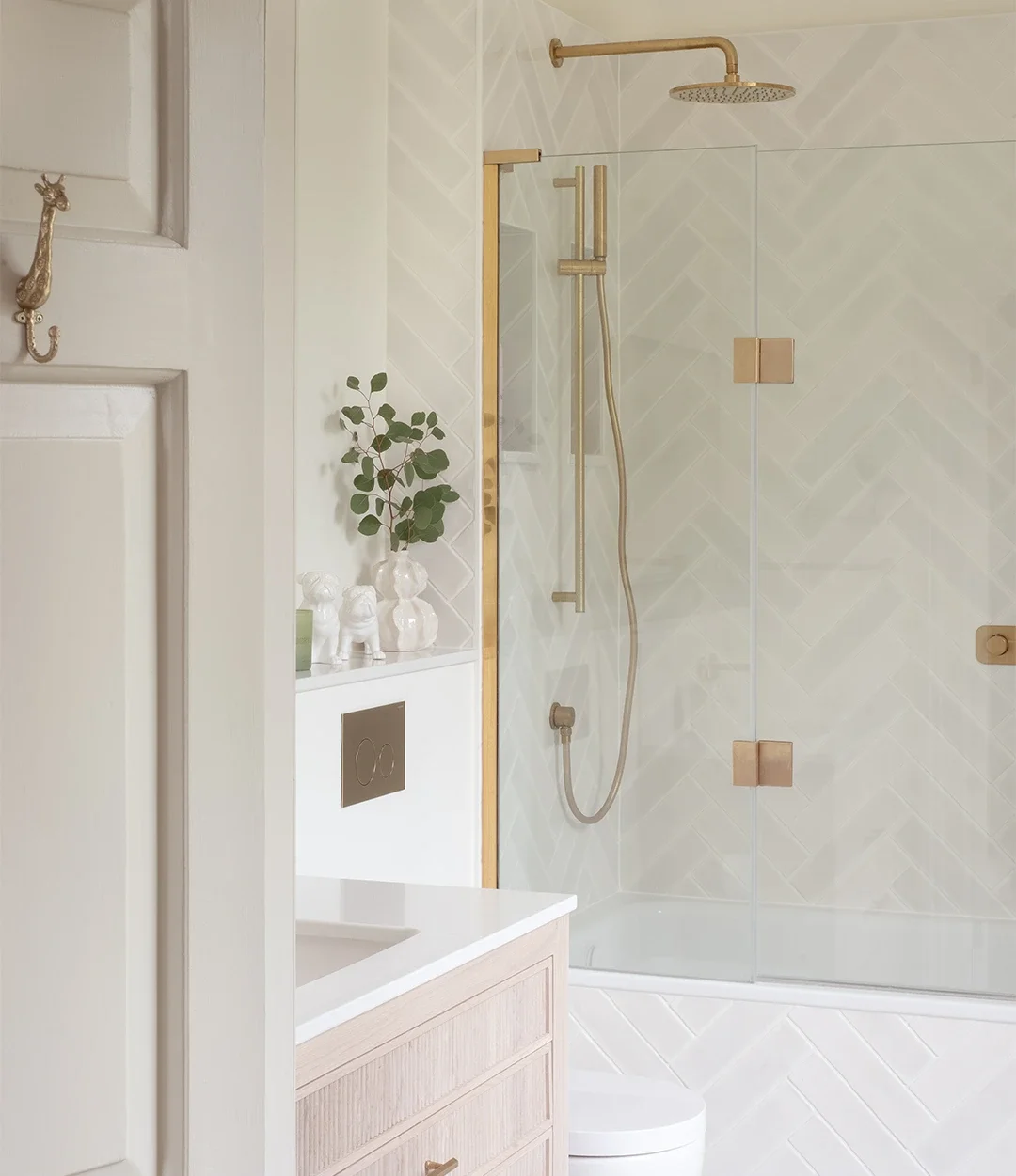 Serene ensuite bathroom with herringbone wall tiles, fluted vanity unit and brushed brass finishes